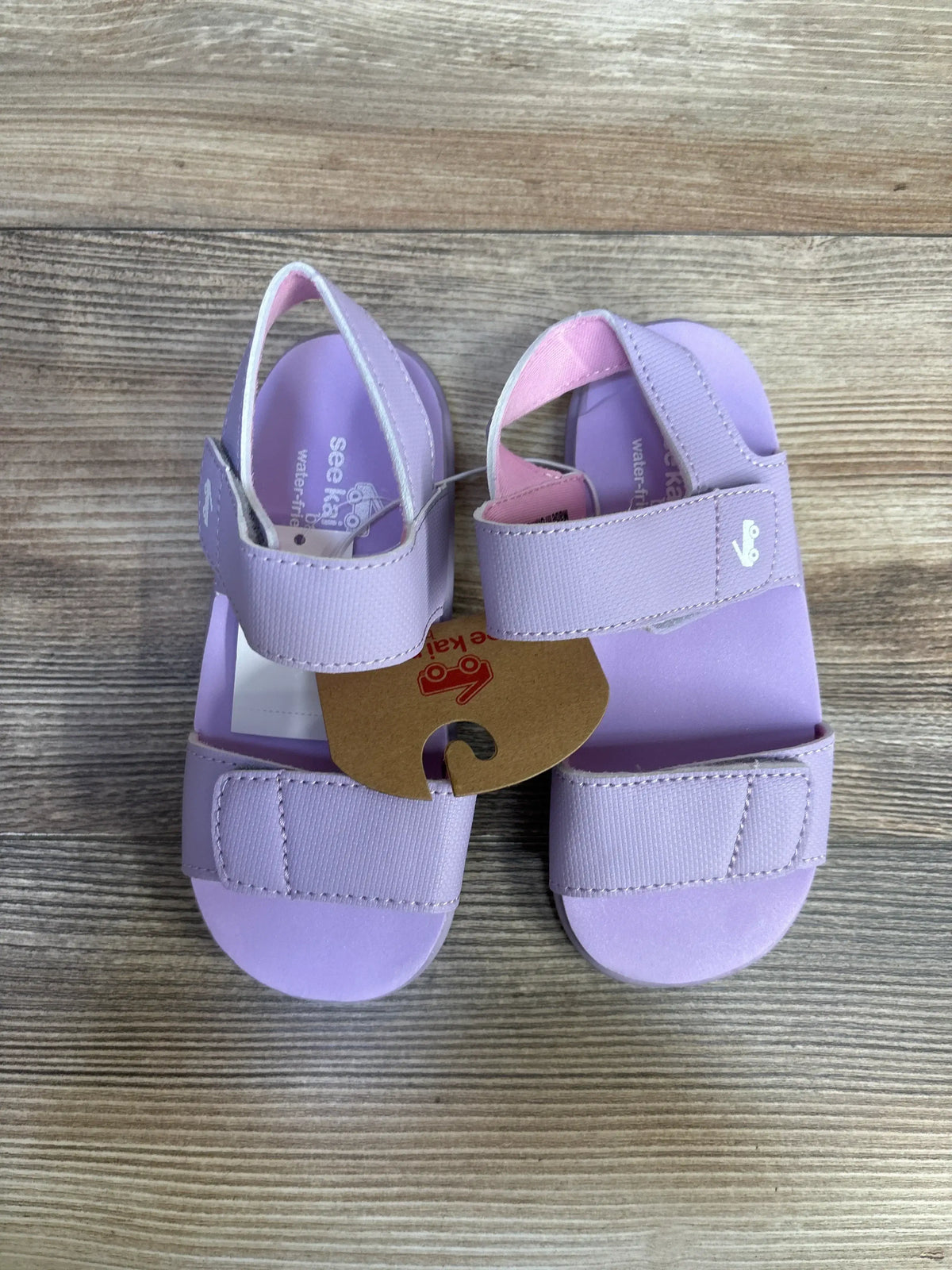 Top-down view of lavender See Kai Run Jaylen toddler sandals, size 11C, showing adjustable Velcro straps and open-toe design on wooden background