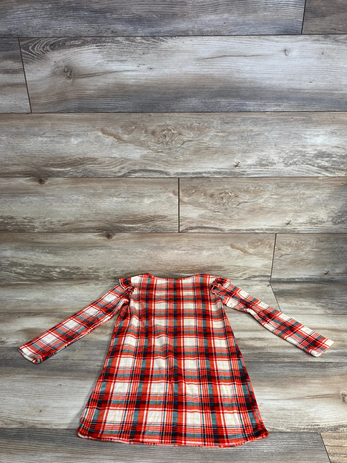Red and white plaid long sleeve girls dress on wood background