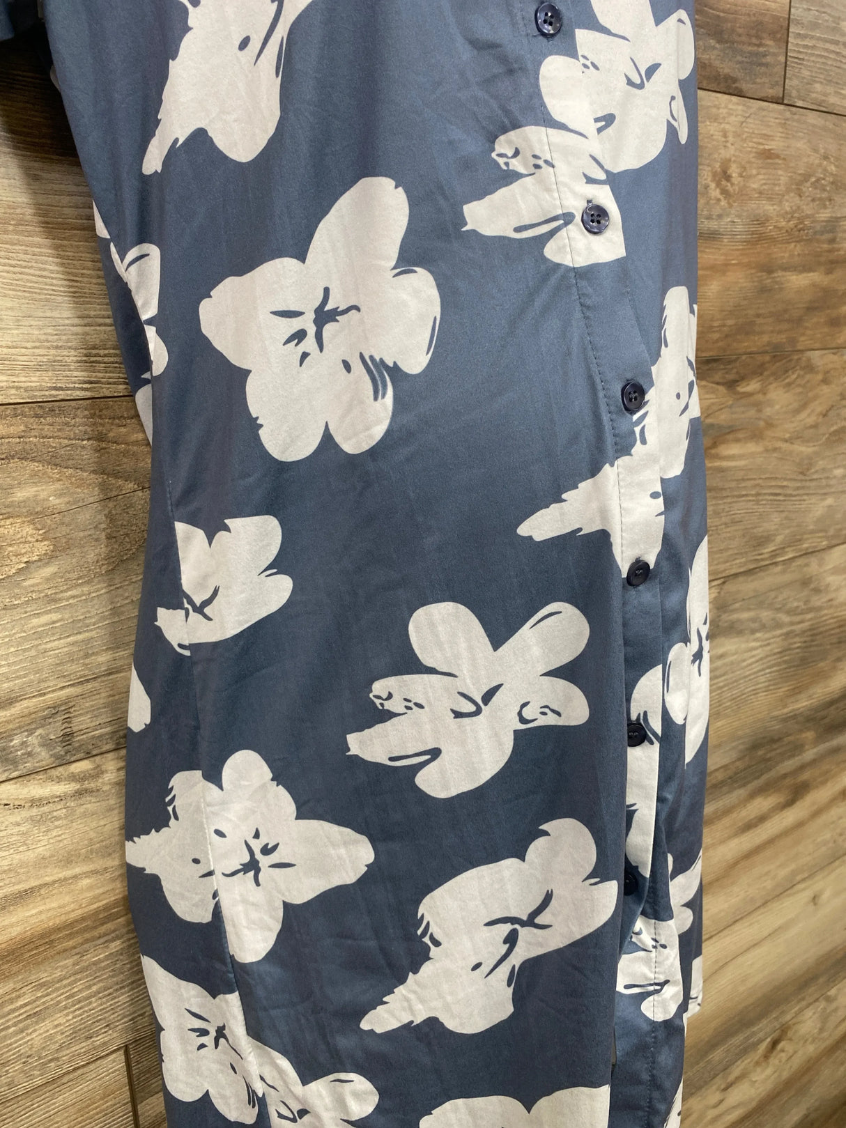 Front close-up of Ekouaer grey button-up nightgown showing white floral print and navy buttons on wood background