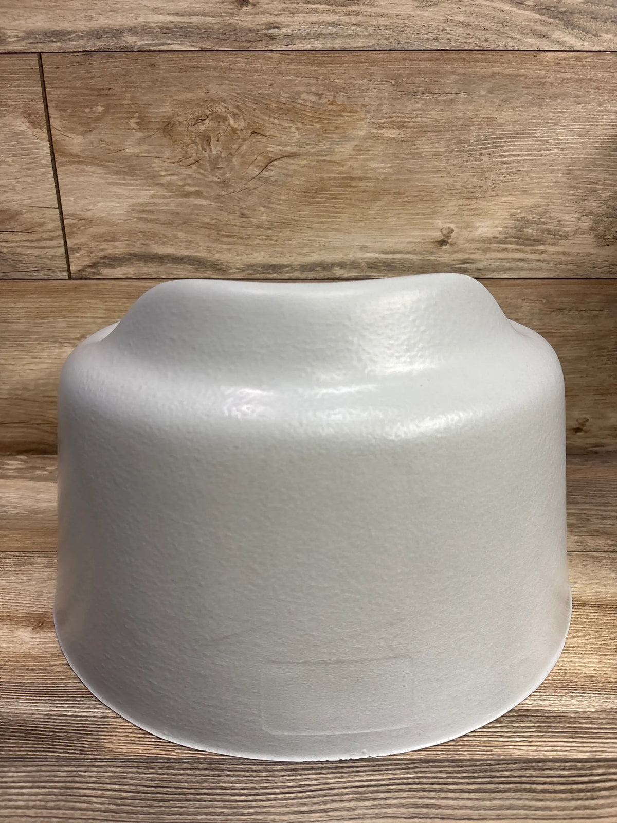 Rear view of grey Bumbo Floor Seat showcasing its contoured design on a wood floor