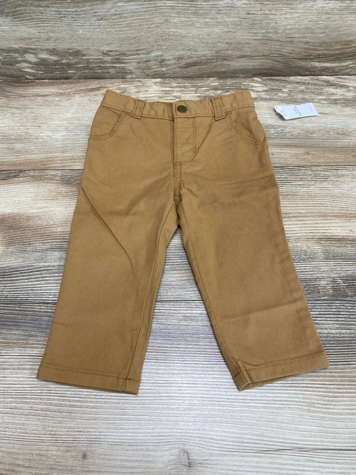 Front view of NEW Old Navy 360 Stretch Skinny Pants in bandolier brown sz 12-18m showcasing five pocket styling with hangtag on wood plank background