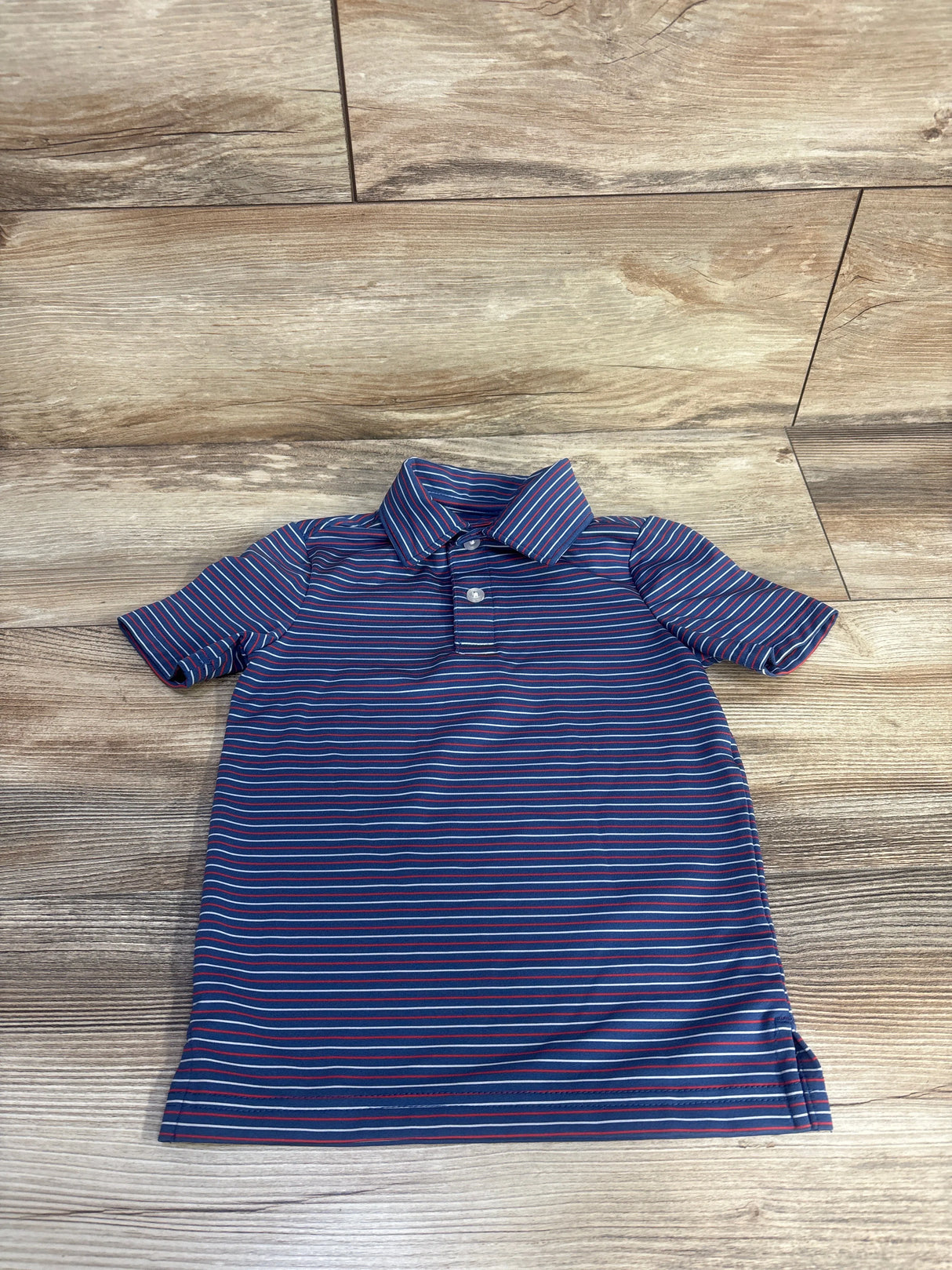 Front view of Class Club Stripe Synthetic Polo in blue with allover stripes, polo collar, and short sleeves on wood flooring