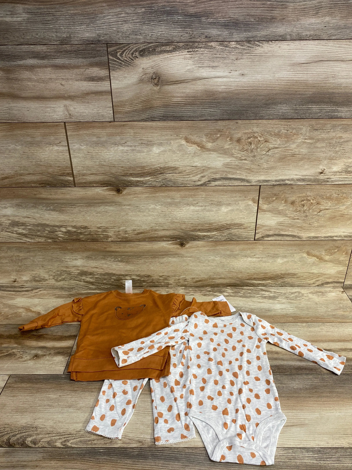 Front view of baby lion sweatshirt set: caramel top with ruffle shoulders and lion face, and polka-dot bodysuit and pants
