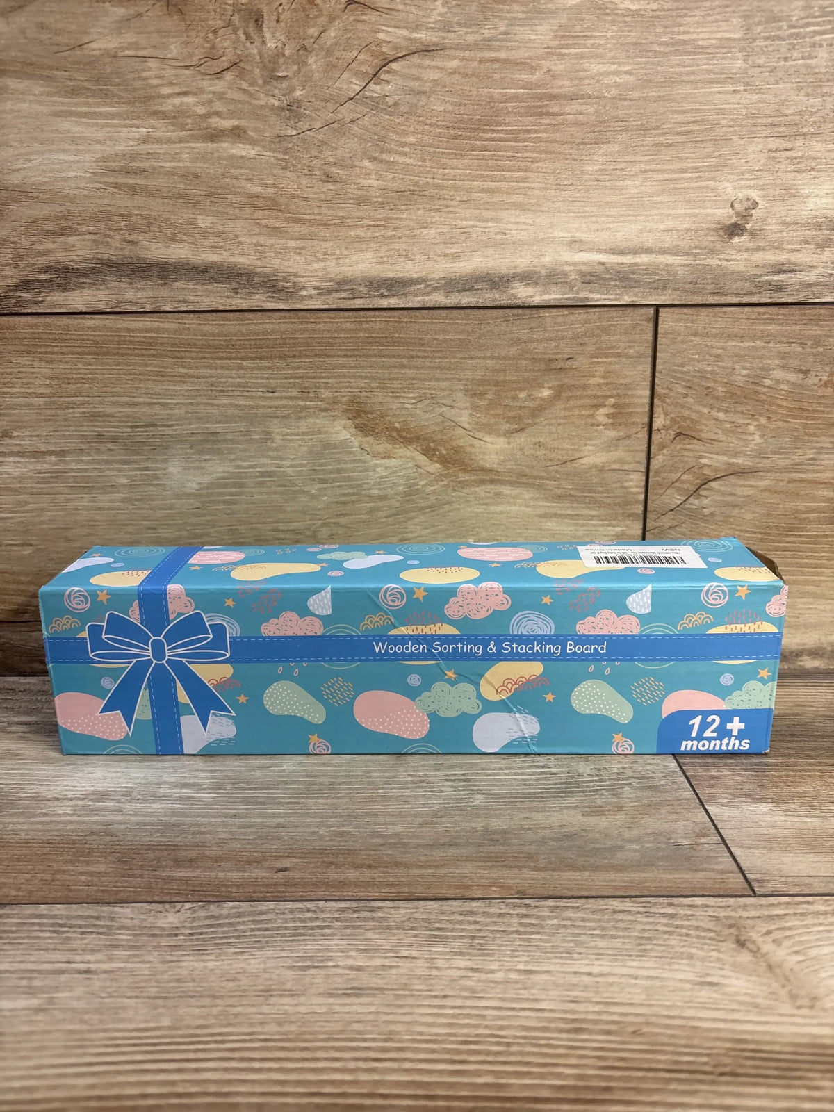Front view of the HelloWood Montessori sorting and stacking board box showcasing colorful packaging and 12 plus months label