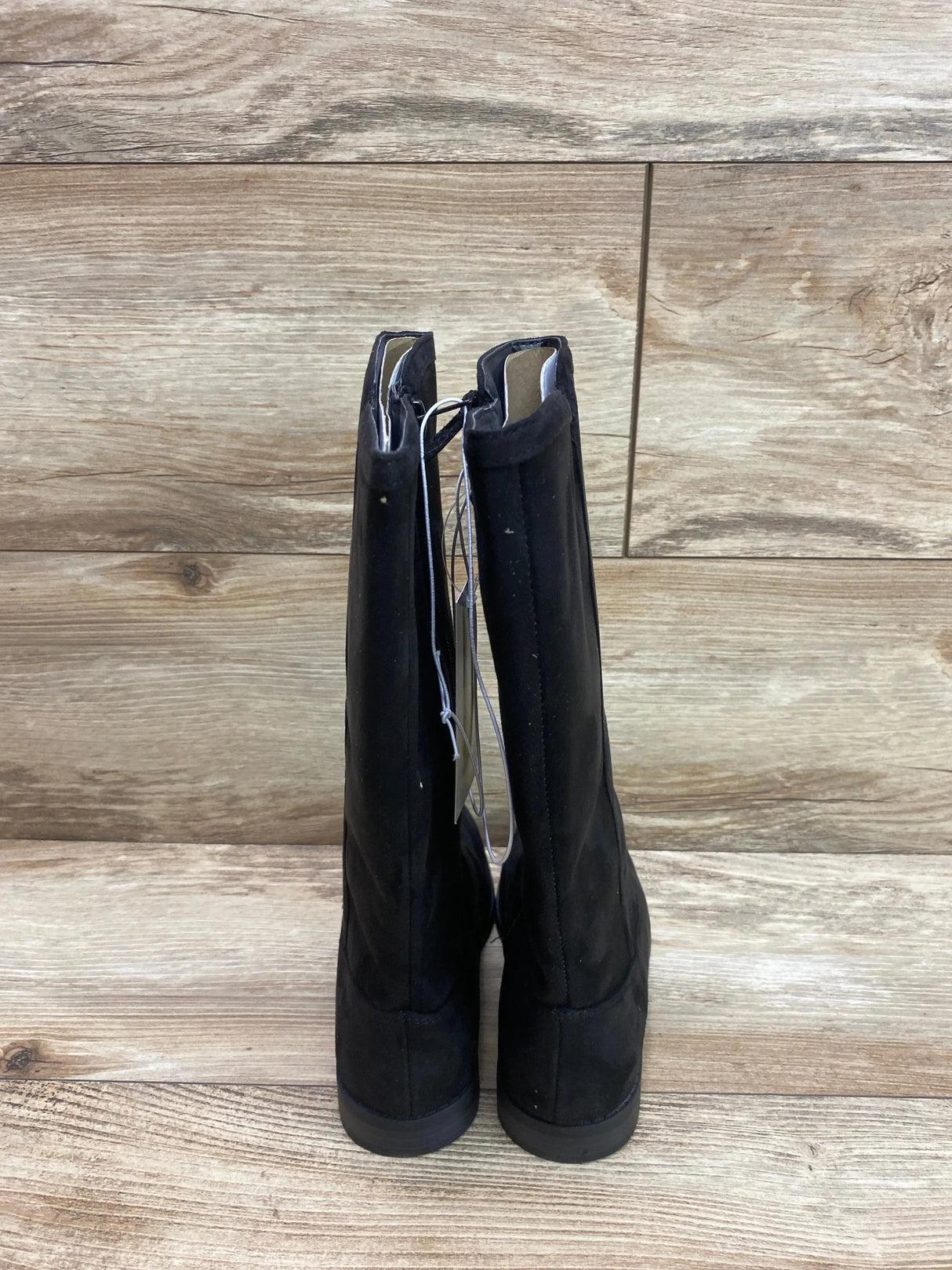 Rear view of black Cat & Jack Mylah tall riding boots showing pull tabs, low heels, and size 1Y tag on wood plank background