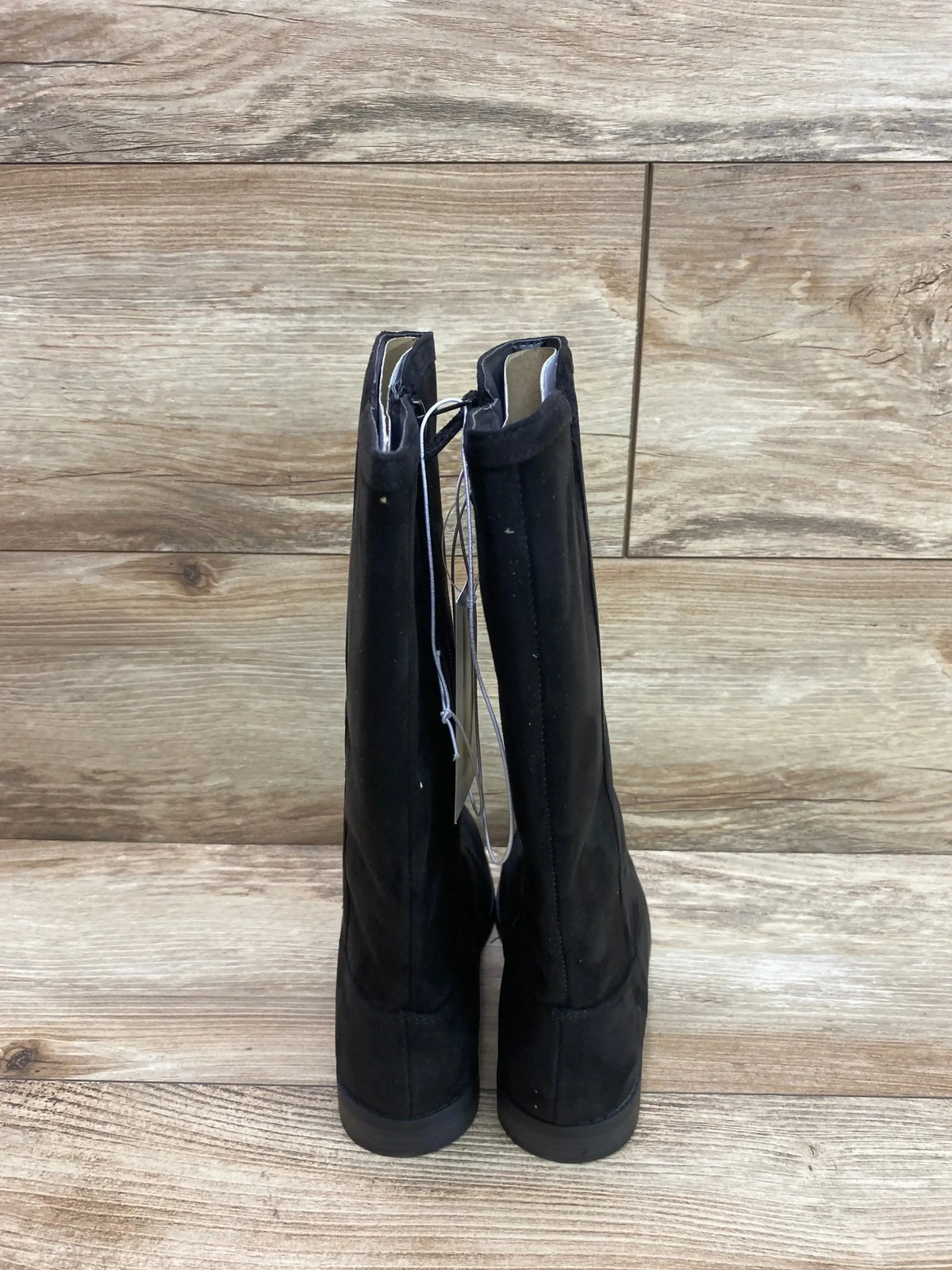 Rear view of black Cat & Jack Mylah tall riding boots showing pull tabs, low heels, and size 1Y tag on wood plank background