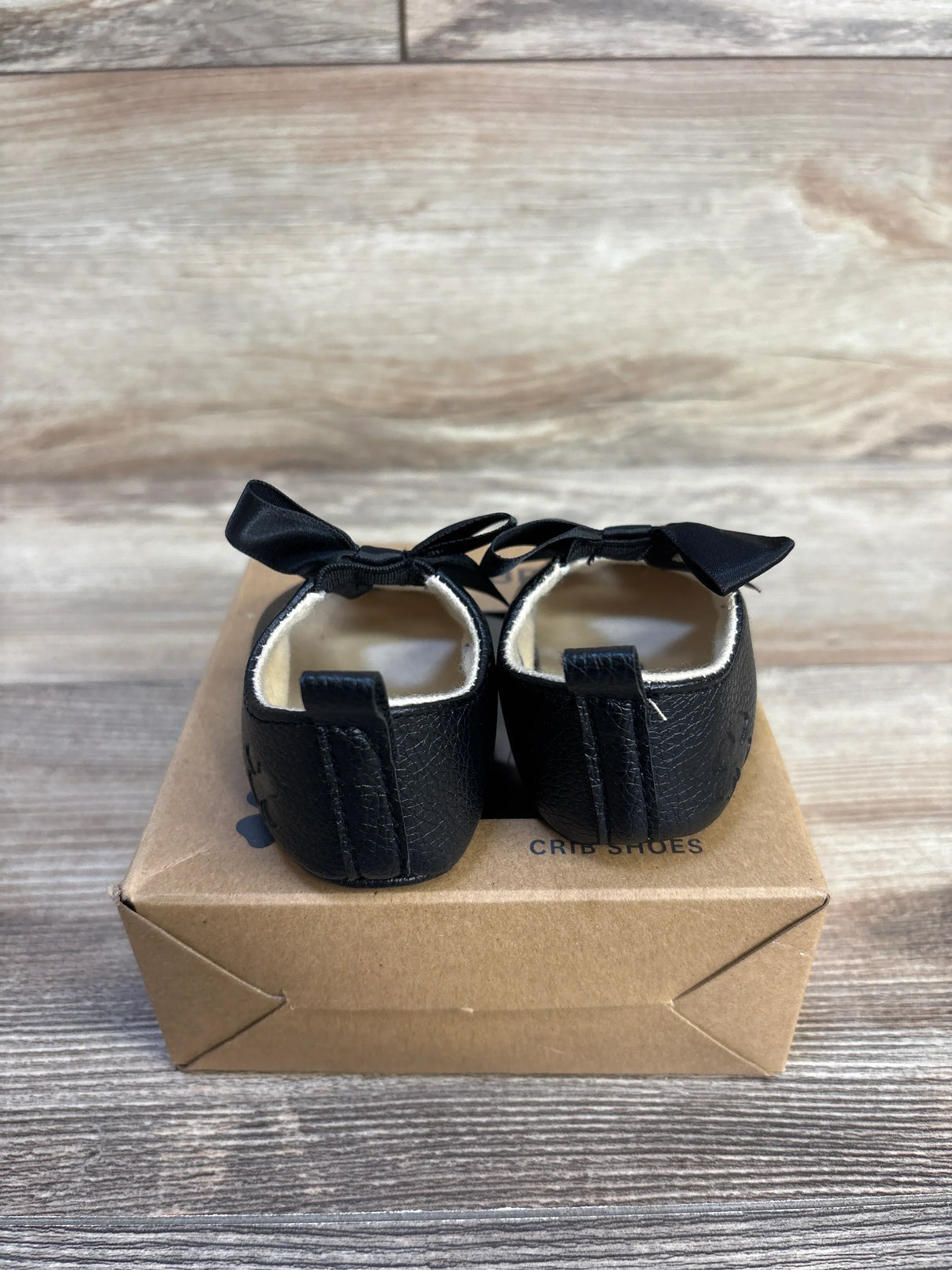 Black baby crib shoes with bows, soft sole, on box
