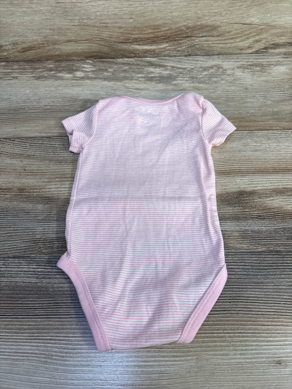 Flat lay of Nike Striped Bodysuit Pink sz 6m showcasing short sleeves and fine stripes with a wood-grain background