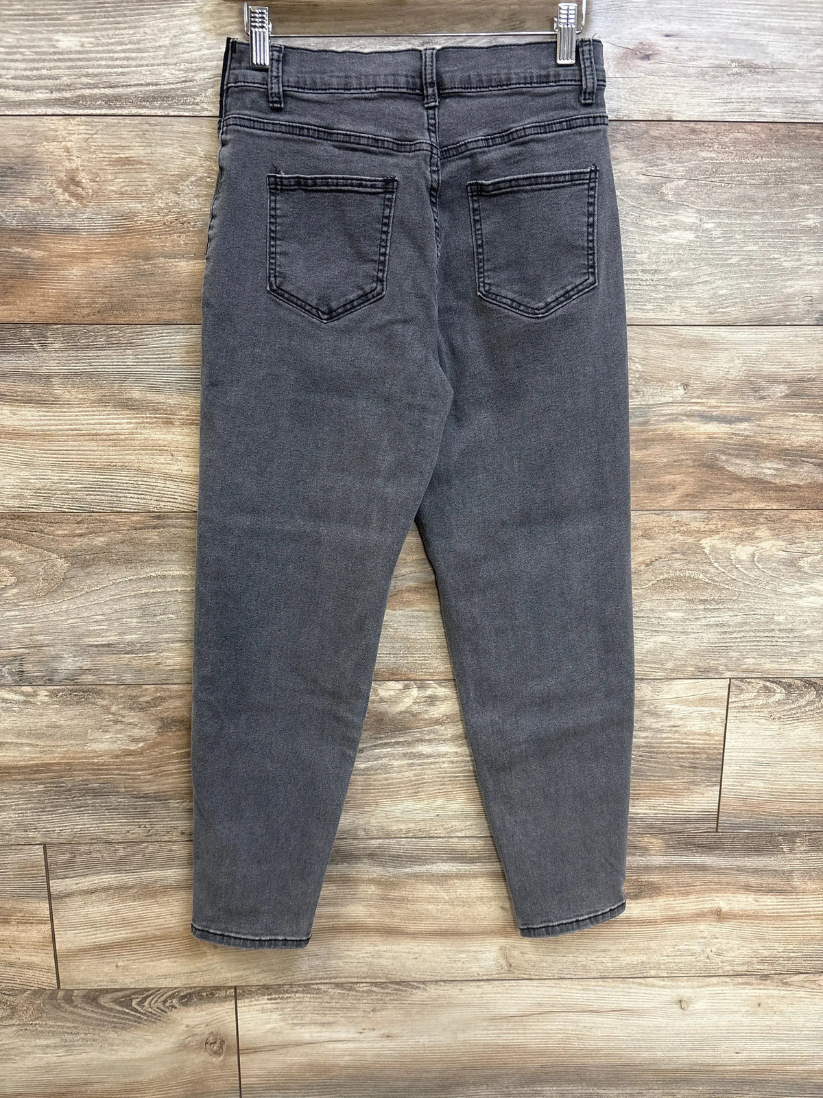 Back view of Maternity Jeans Grey sz Small showcasing washed grey denim slim leg with back pockets clipped on hanger over wood plank floor