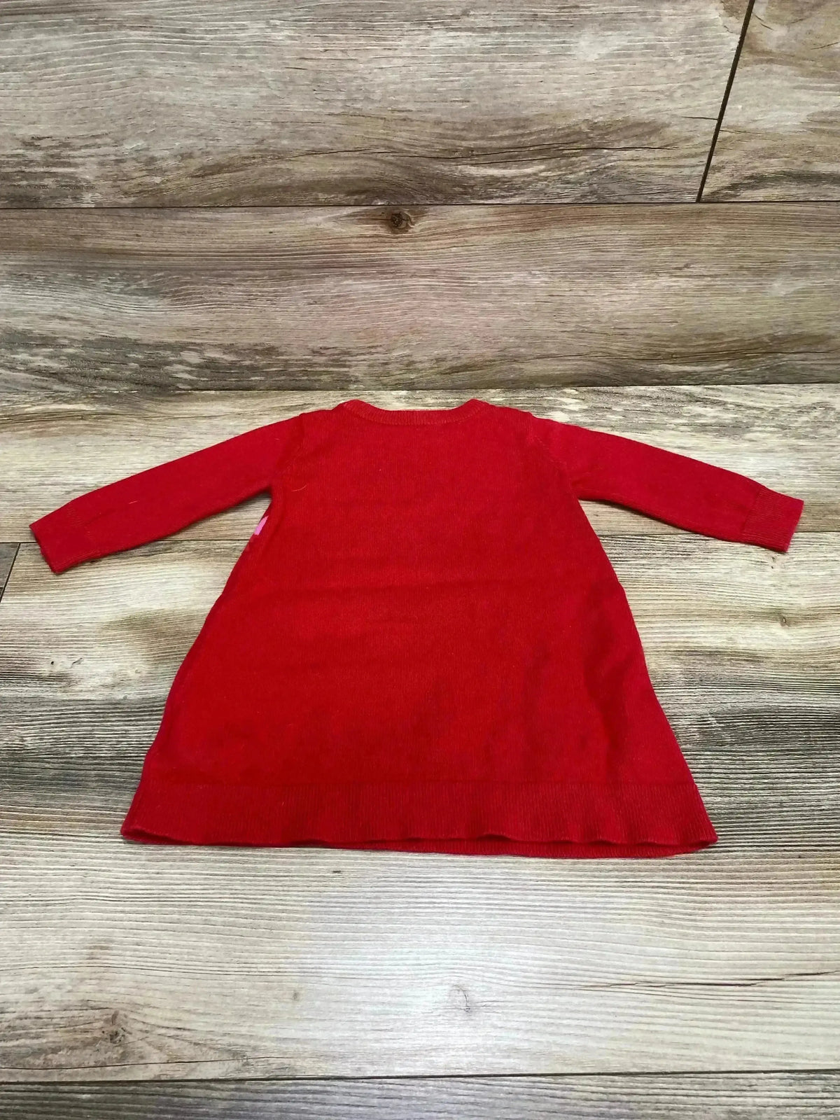Flat lay of Baby Gap red sweater dress (back view) showing long sleeves and A-line skirt on wood floor