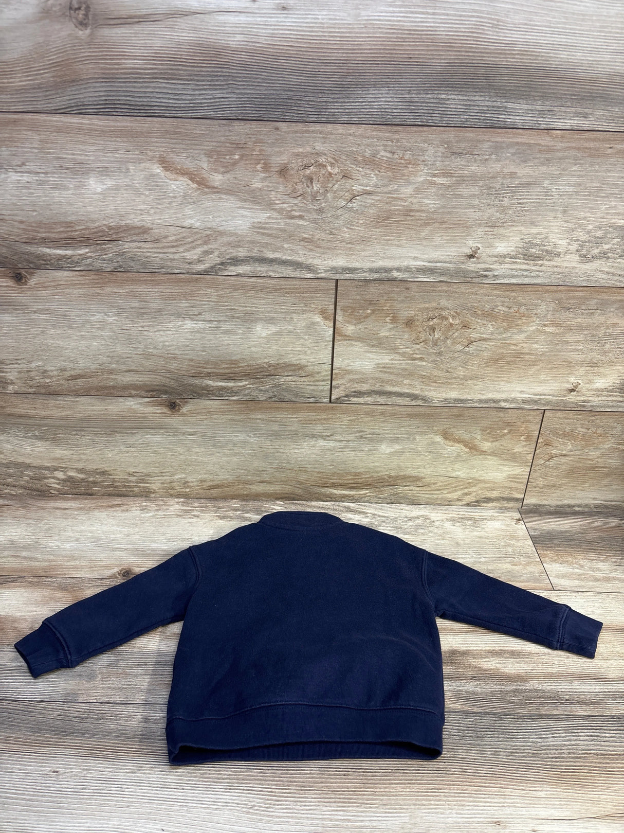 Back view of Baby Gap VintageSoft navy quarter-zip pullover showing ribbed cuffs and long sleeves on wood floor