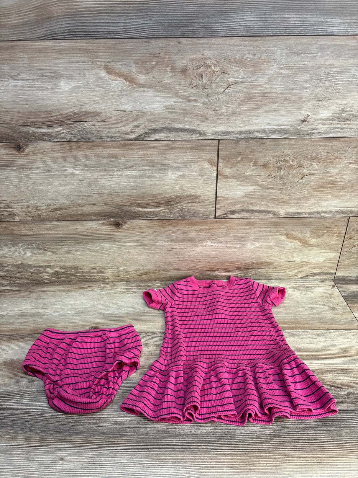Flat lay of girls Ralph Lauren pink striped dress and matching bloomers showcasing ruffled hem and ribbed knit on wood floor