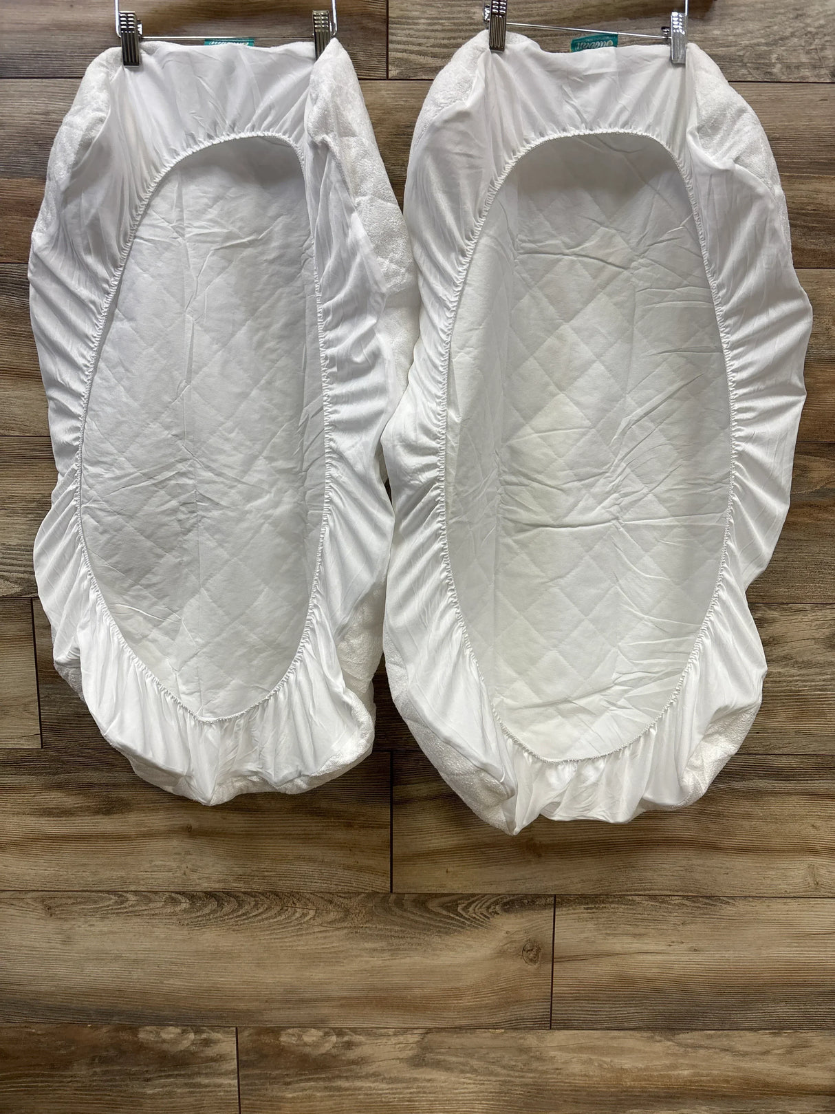 Pair of white quilted bassinet mattress covers on wooden floor, baby bedding essentials