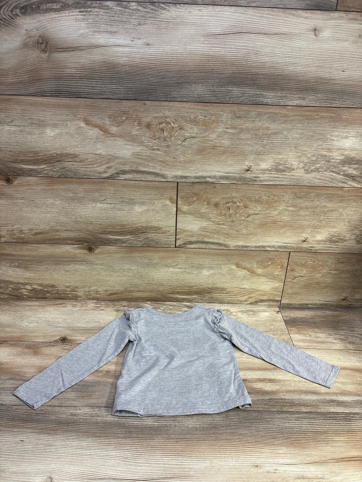 Back view of Disney Junior Mickey Mouse Boo Crew 4T long sleeve toddler shirt with ruffle shoulders on wood background