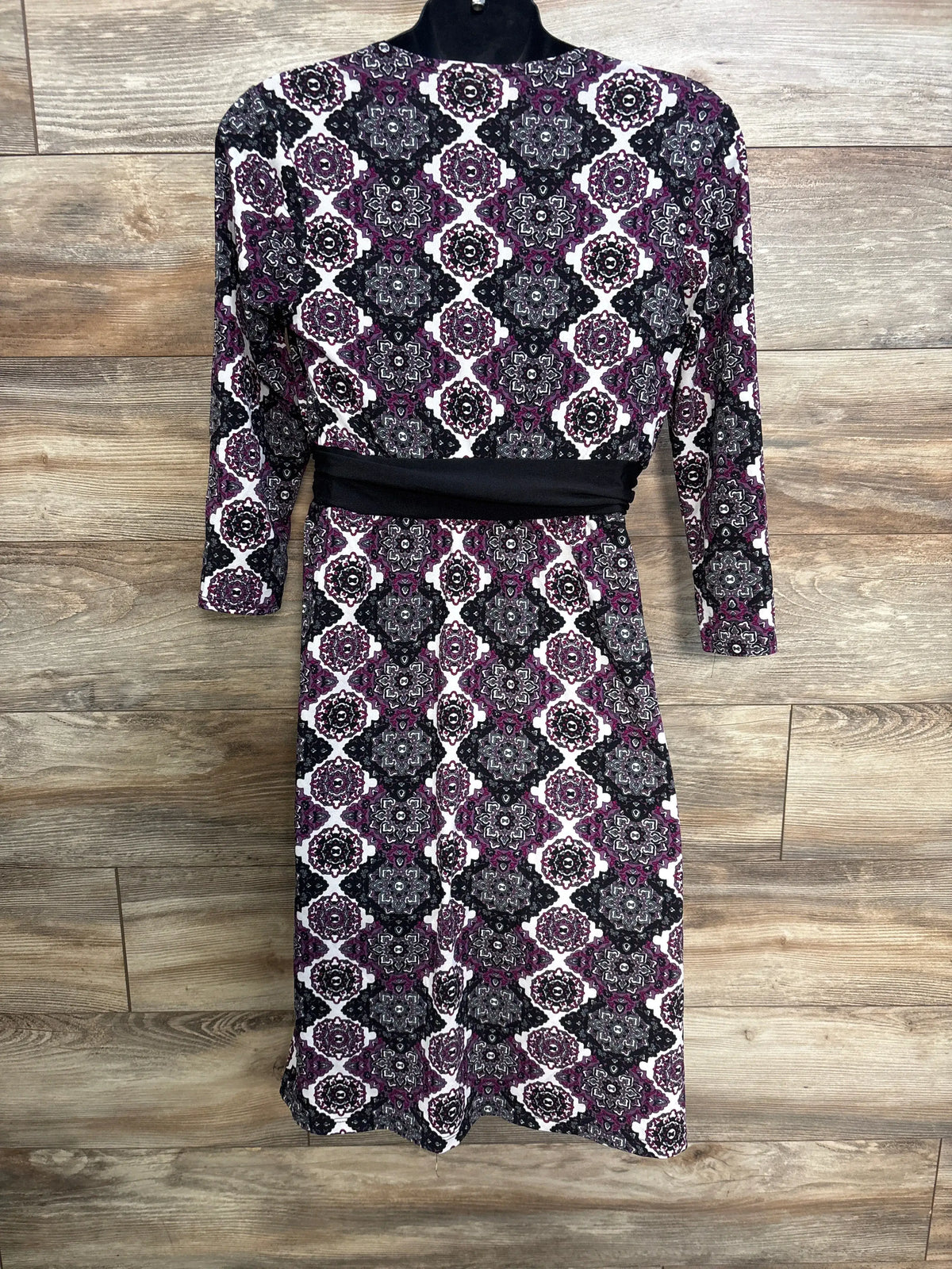 Front view of Motherhood Maternity geometric dress showcasing purple pattern and black waist band on wood floor
