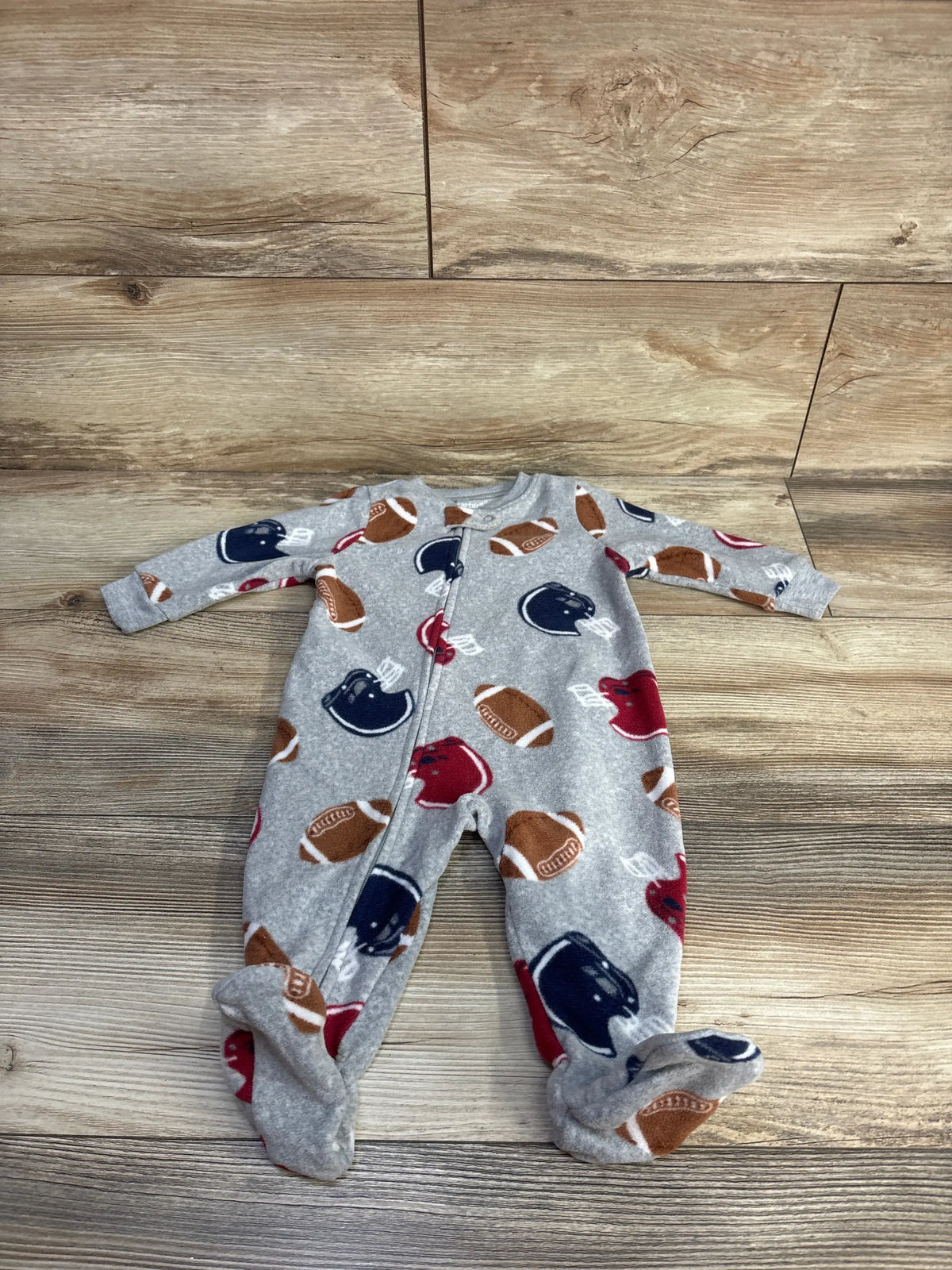 Front view of Carter’s football blanket sleeper showing grey football print, footed legs, and snap closure