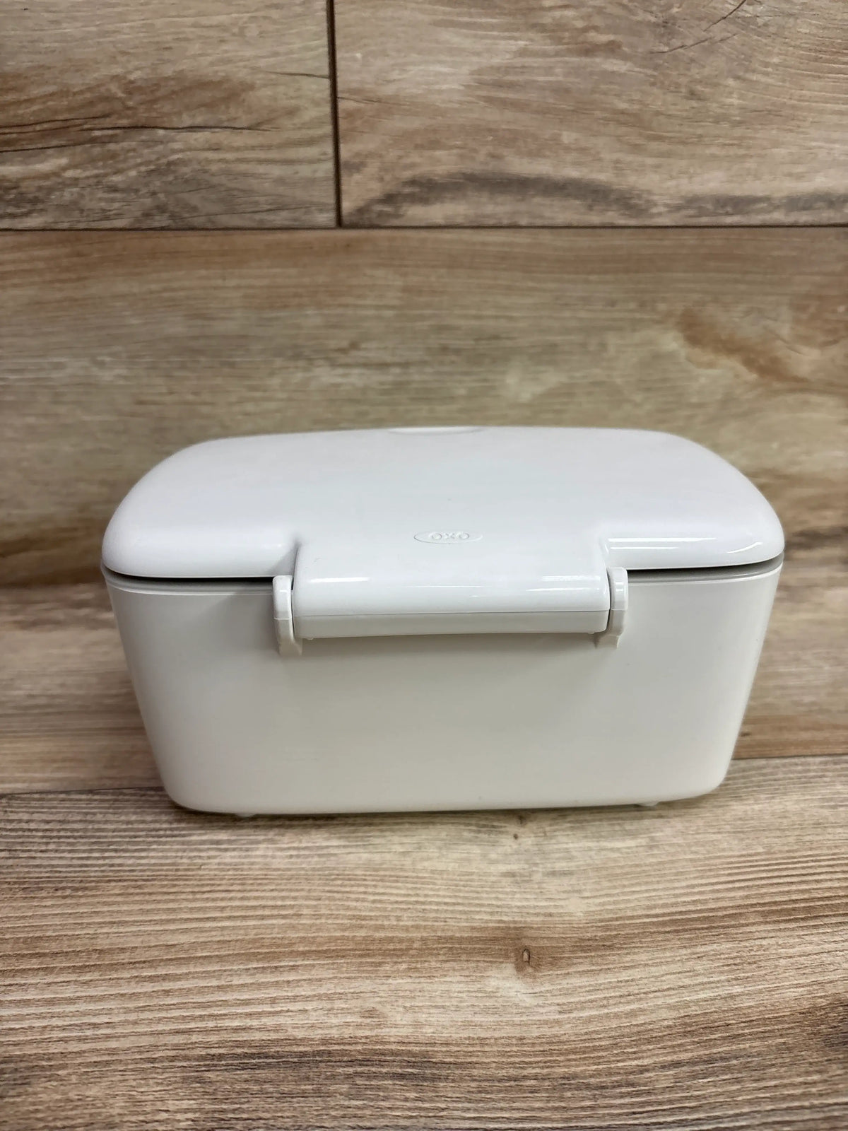 Front view of OXO Tot Perfect Pull Wipes Dispenser showcasing a white lidded rectangular design on a wood surface
