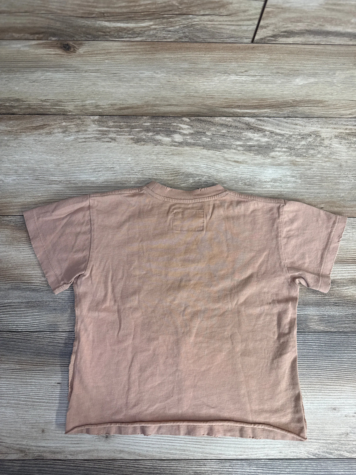 Back view of a plain brown cotton short-sleeve t-shirt on wooden floor