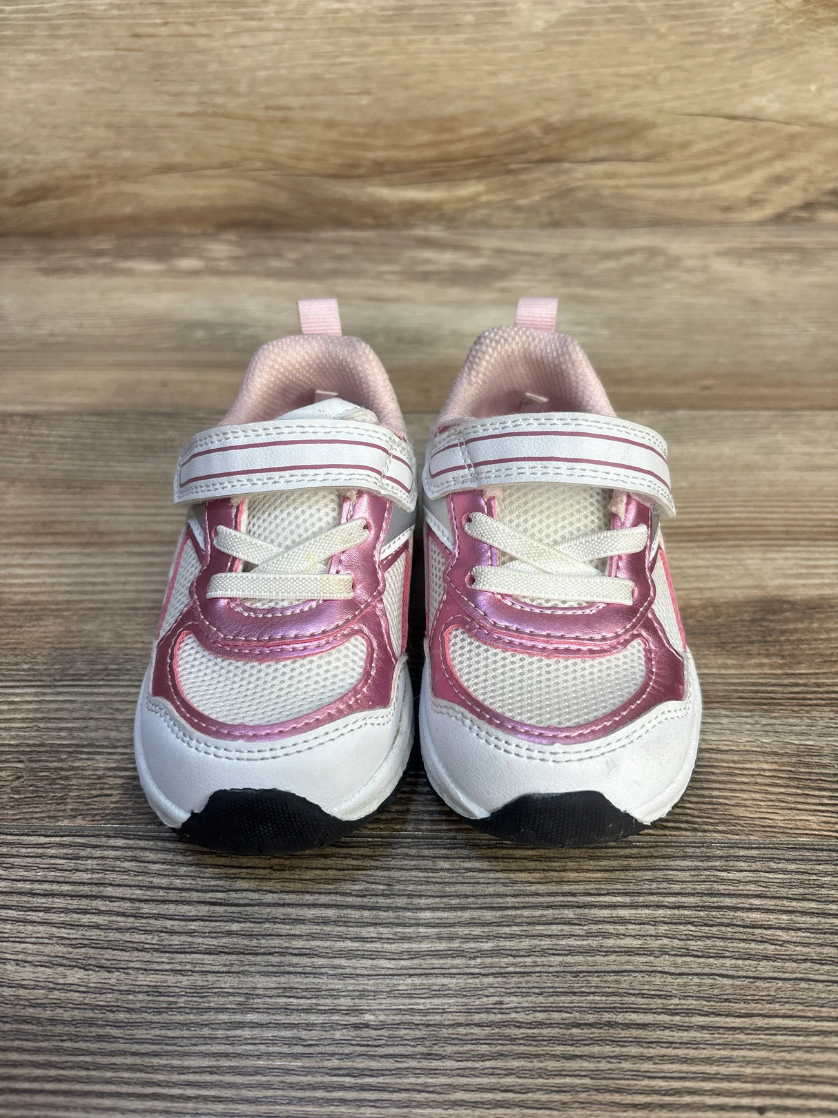 Pink and white toddler sneakers with Velcro straps on wood background
