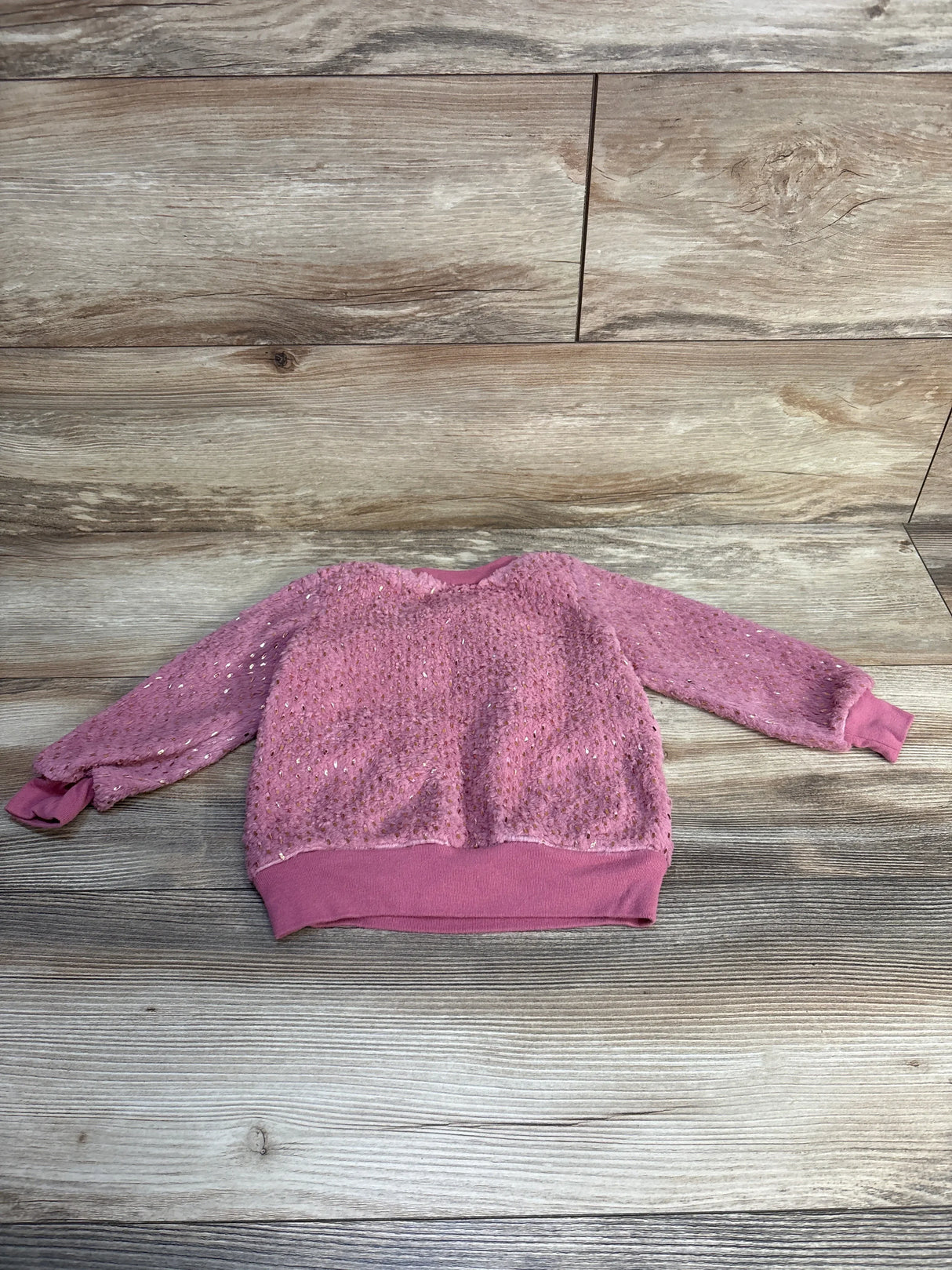 Pink toddler sequin sweater with long sleeves on wood background, gently used kids clothing