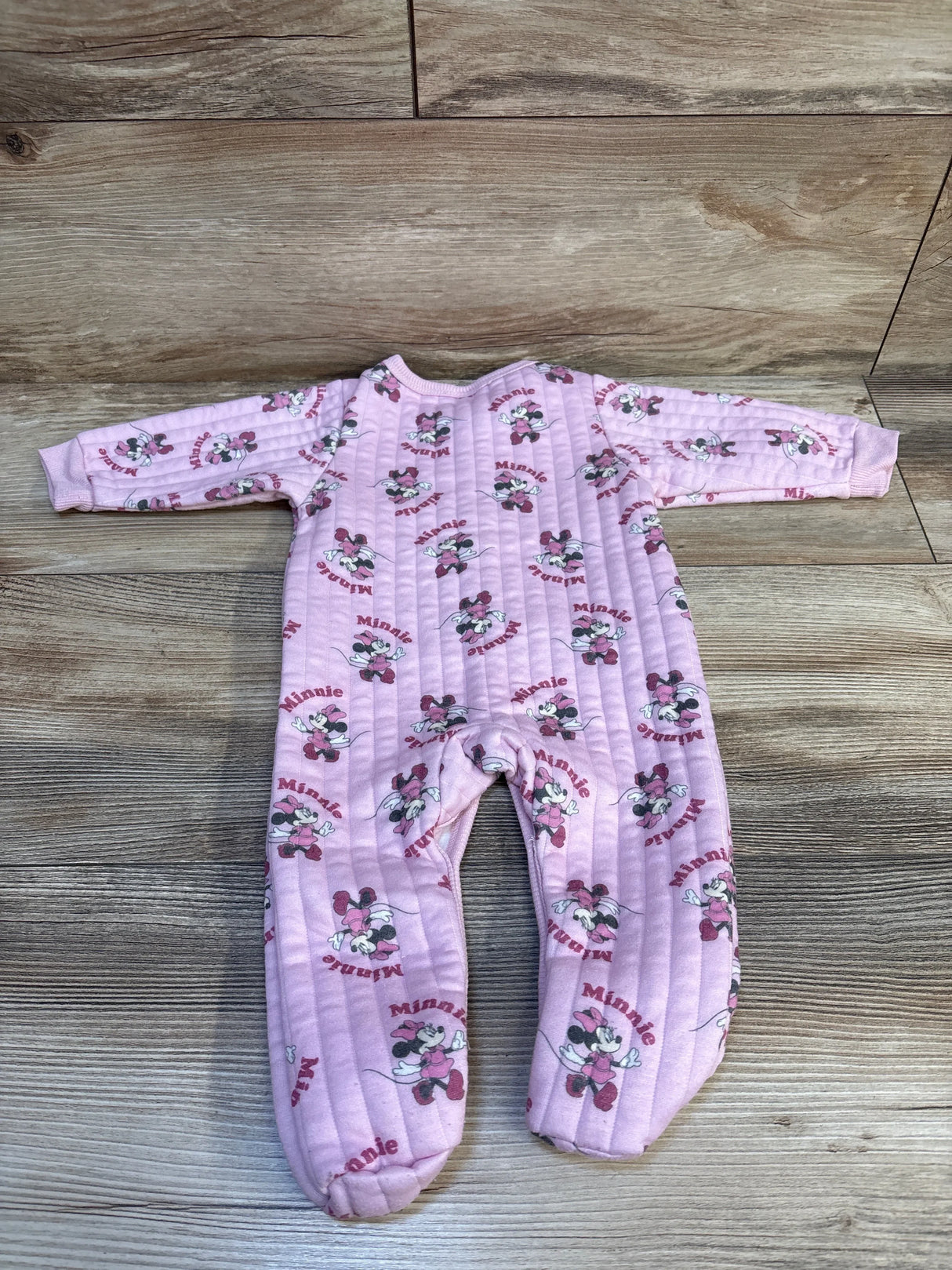 Pink baby sleeper featuring Minnie Mouse print, long sleeves, and quilted fabric on wood floor