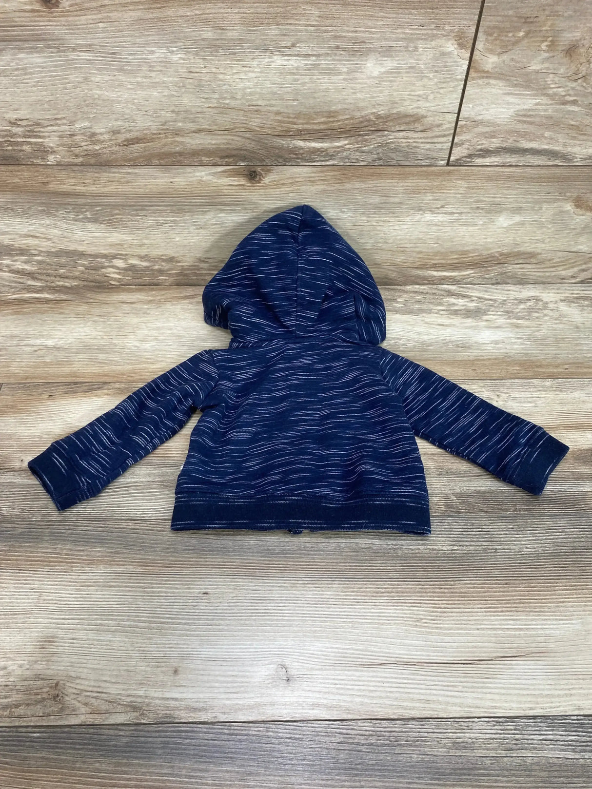 Back view of navy full-zip toddler hoodie (12 months) showcasing hood and white heathered stripe pattern with wooden floor background