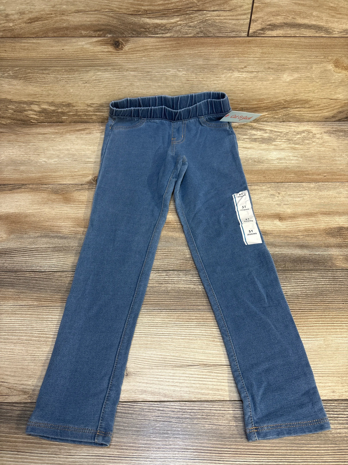 Blue toddler girl jeggings with elastic waistband displayed on wood floor
