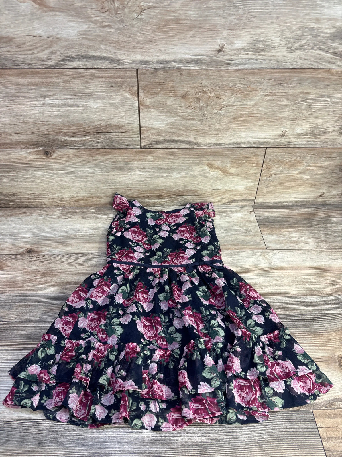 Front view of Janie & Jack navy floral chiffon dress showcasing ruffled tiered skirt on a wood floor