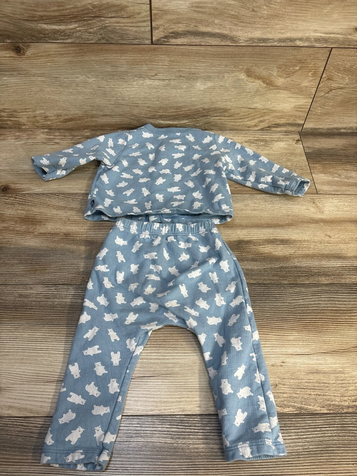 Blue long sleeve baby outfit with white bear print, laid flat on wooden floor