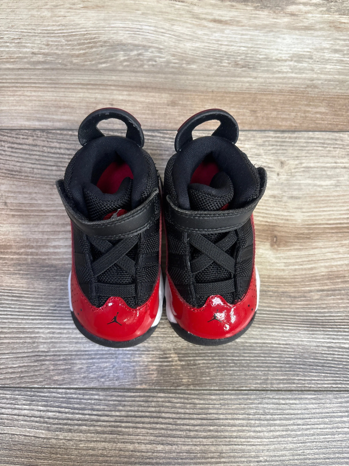 Top-down view of Jordan 6 Rings sneakers size 4C showcasing black mesh upper and red patent toe with Jumpman logo on wood