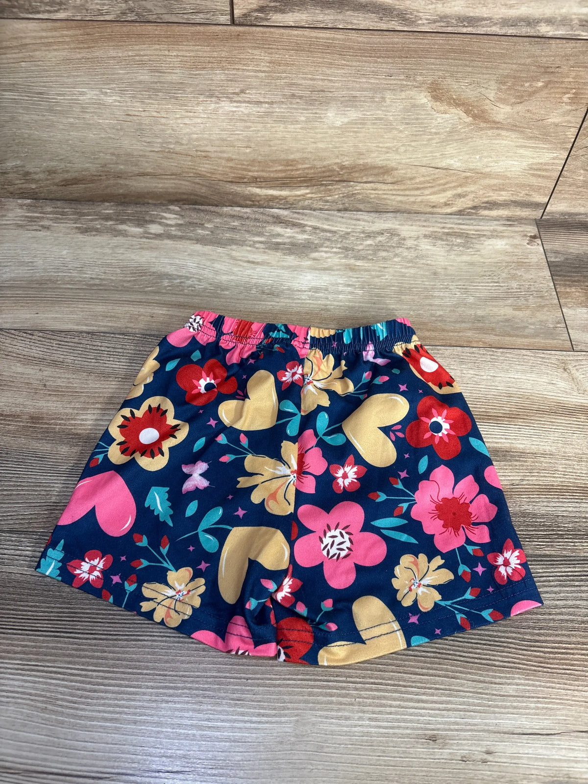 Front view of floral pull-on shorts in navy showcasing colorful floral print and elastic waistband on a wood-grain floor