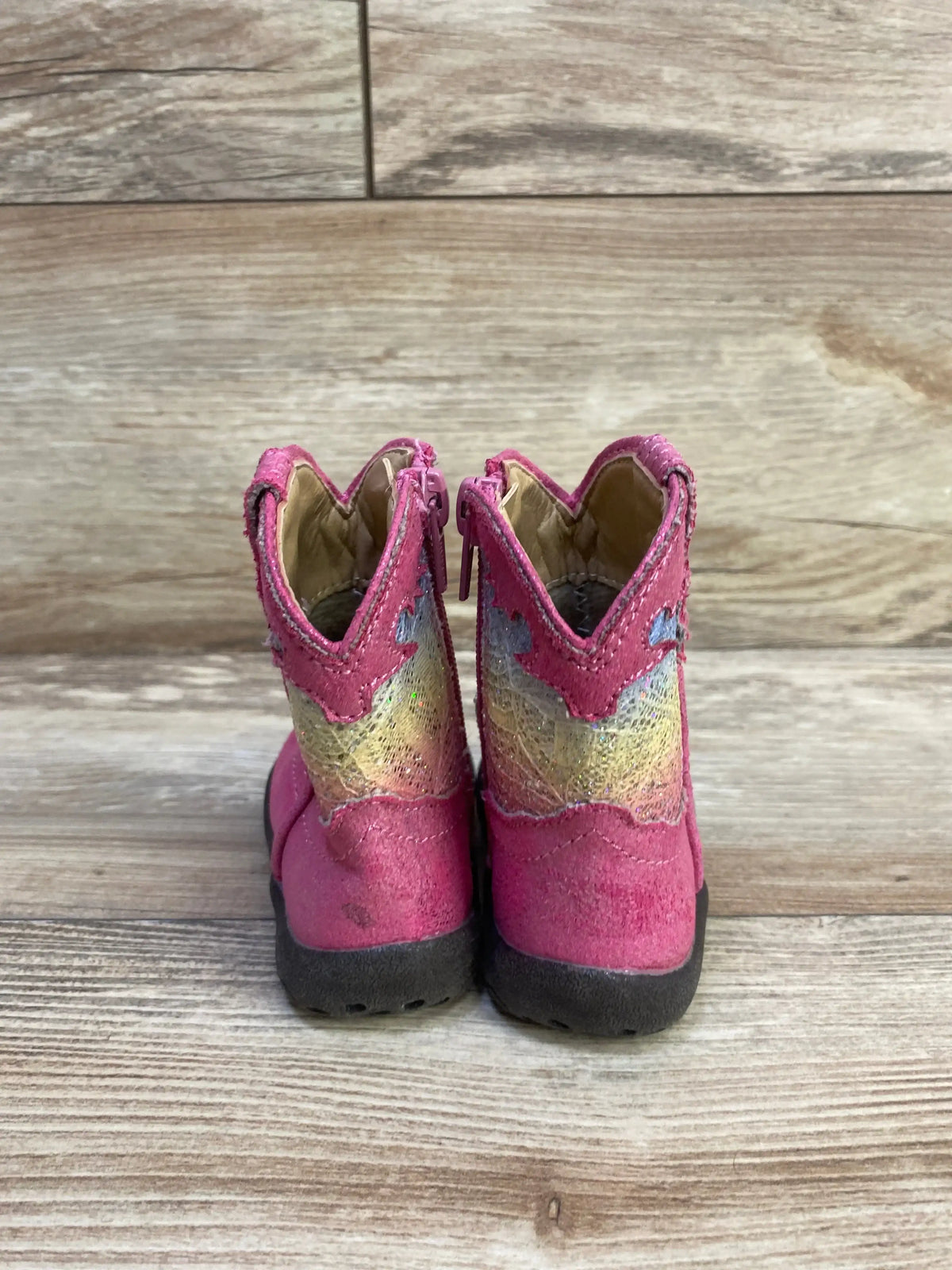 Rear view of Roper infant glitter Cowbabies boots, size 3C, showcasing glitter panels and pink shafts on wood-patterned background