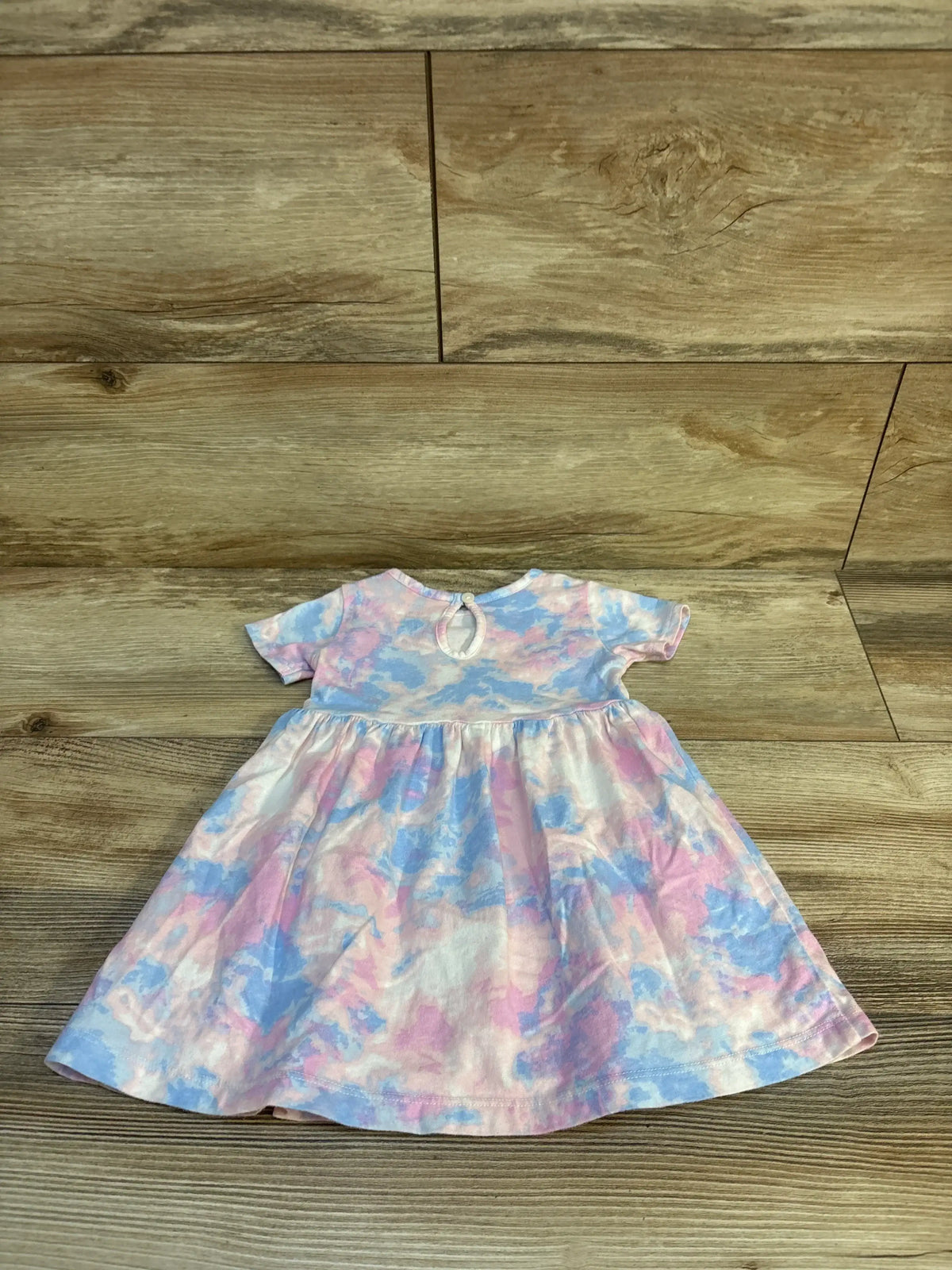 Flat lay of Carter's 12M short-sleeve dress, pastel pink and blue watercolor print with gathered skirt and back keyhole on wood