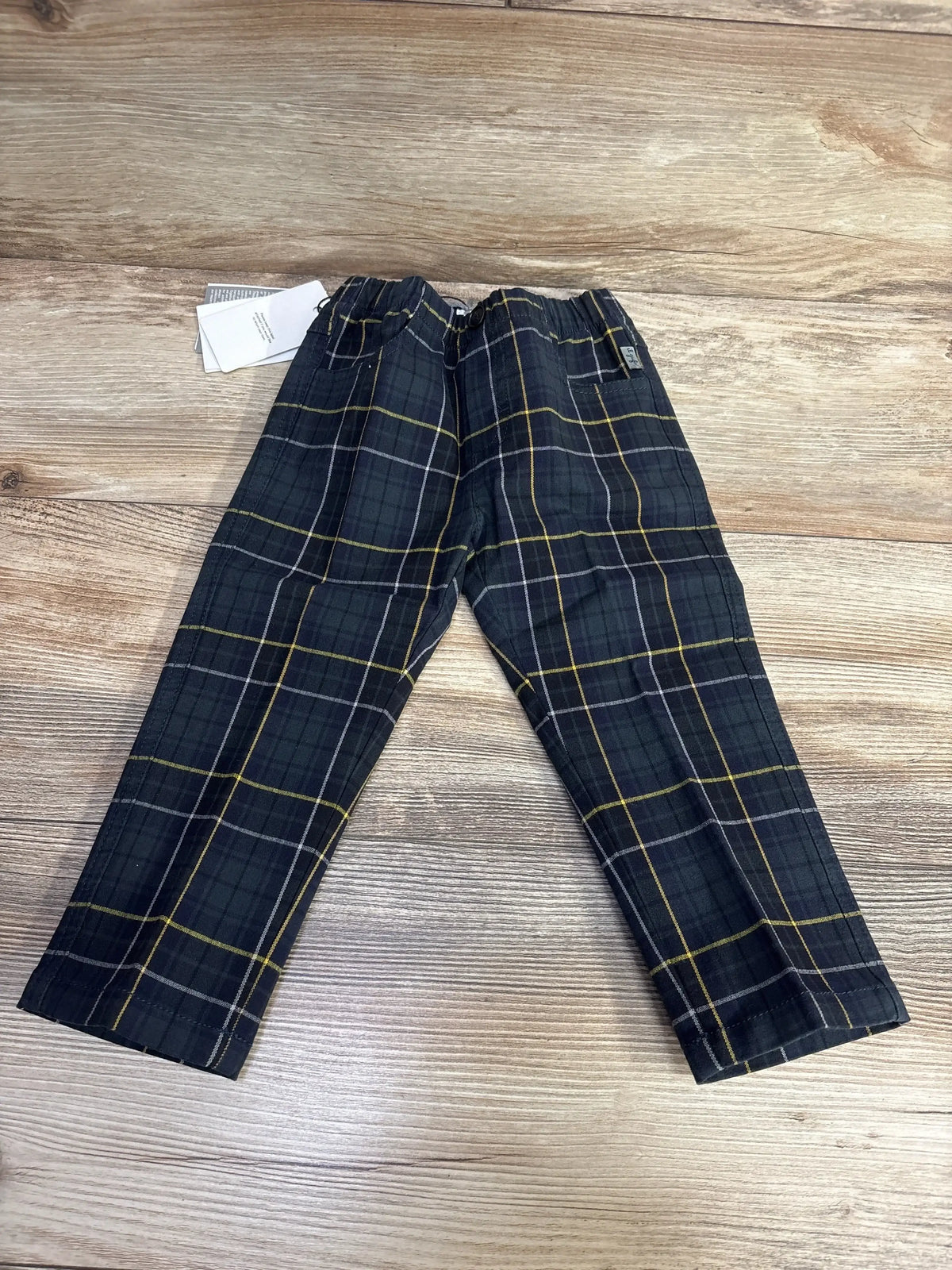 Flat lay of Il Gufo navy checkered trousers showing elastic waist and yellow and white stripes on wood background