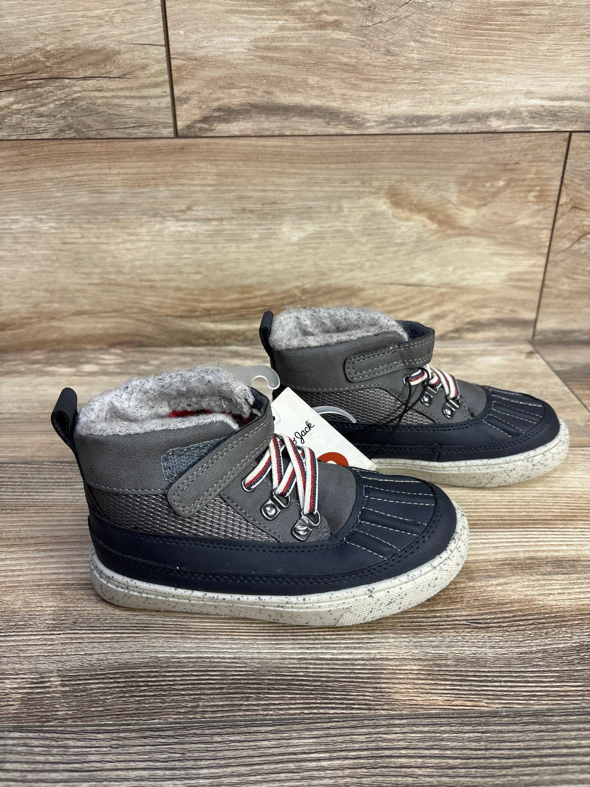 Pair of gray and navy toddler winter boots with white fleece lining on wooden floor