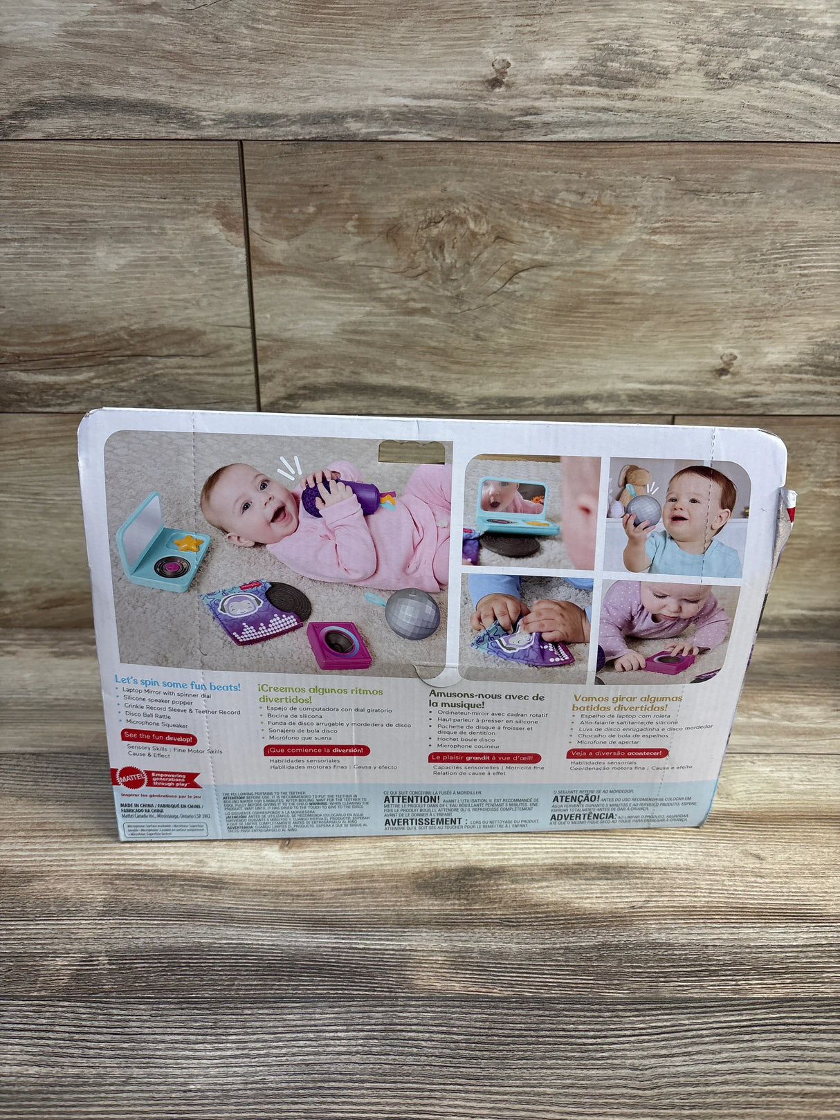 Back of Fisher-Price Mini Me Moments DJ Gift Set box showing included toy pieces and baby photos, photographed on wooden surface