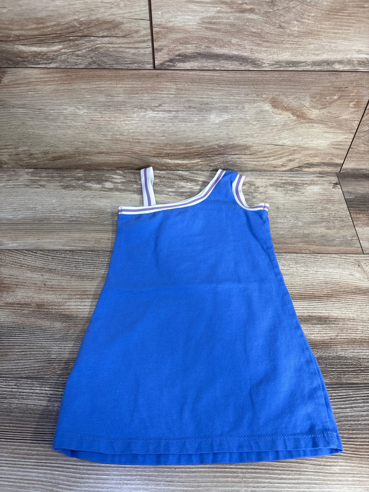 Front view of Disney Stitch tank dress showcasing blue sleeveless styling and striped trim with wood-look background