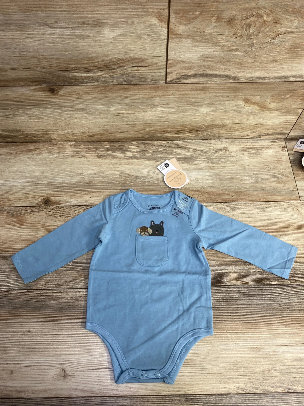 Blue long-sleeve baby onesie with small chest pocket featuring embroidered dog designs