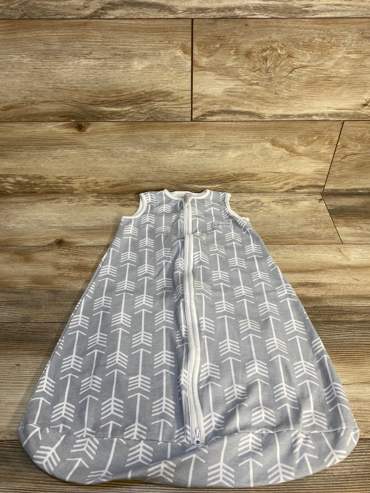 Gray baby sleep sack with white arrow pattern and front zipper on wood background