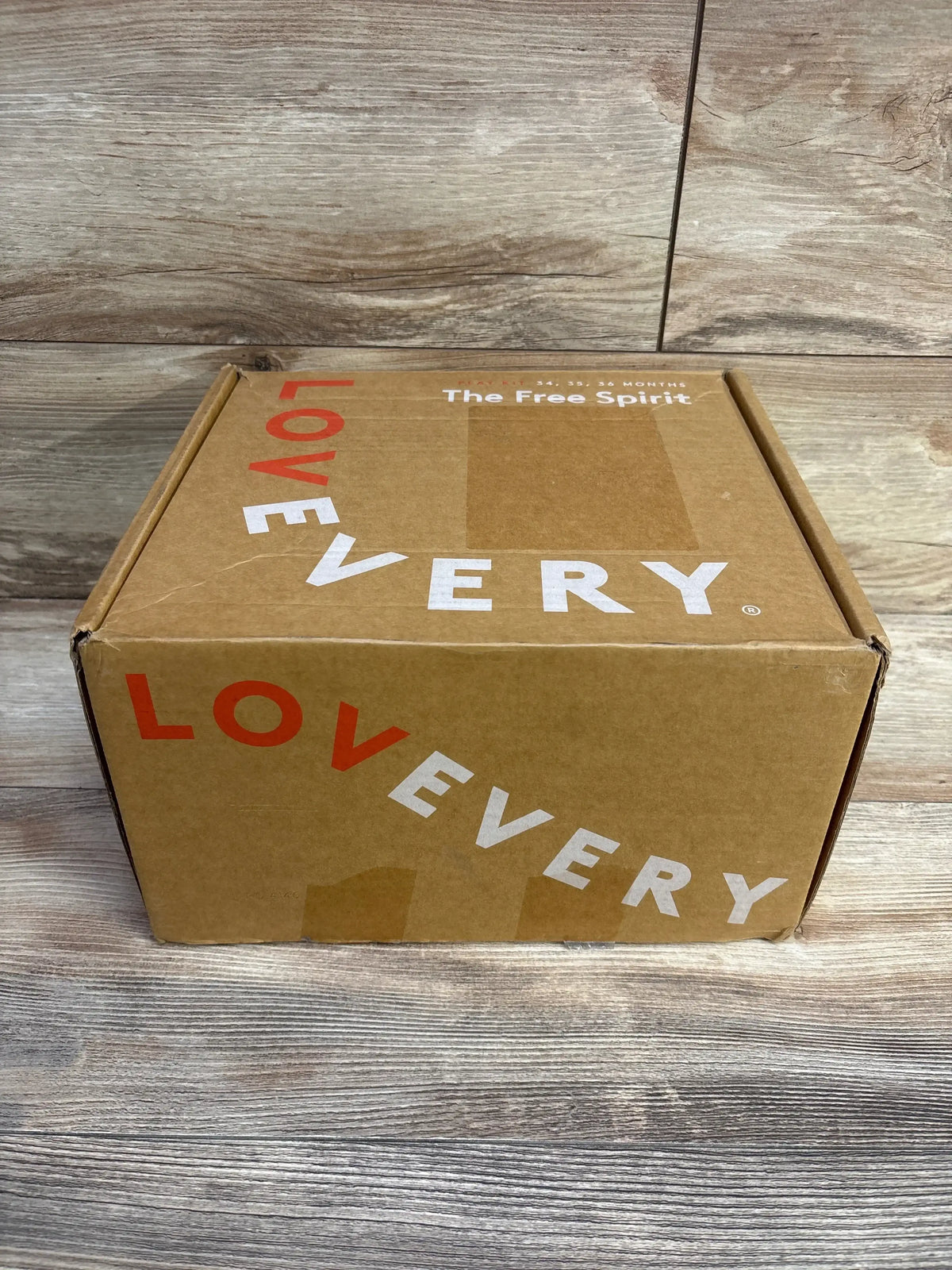 Front view of Lovevery Free Spirit Play Kit box with LOVEVERY logo on wood backdrop