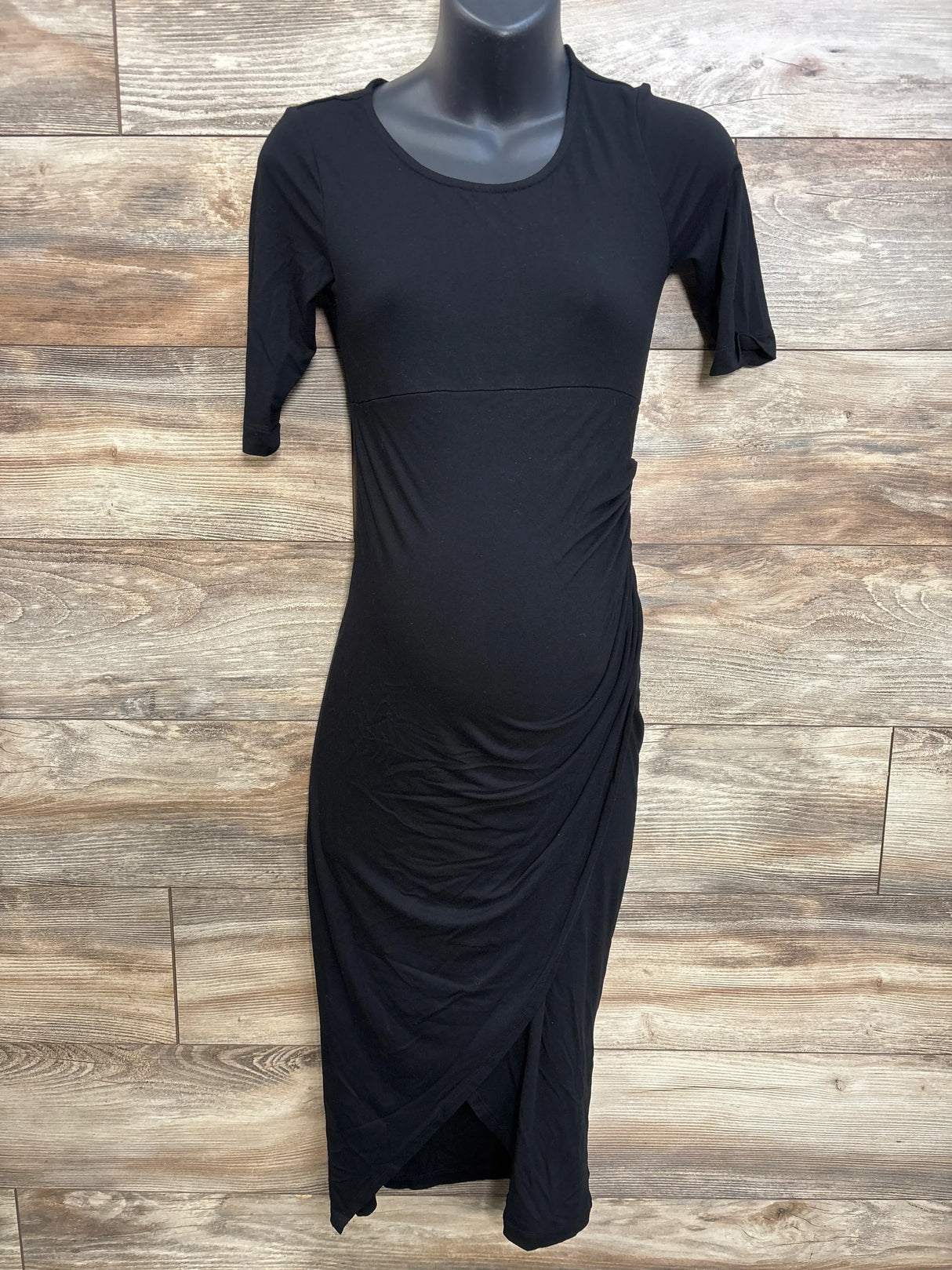 Front view of Isabella Oliver black maternity short-sleeve midi dress showing side ruching and tulip wrap hem on mannequin