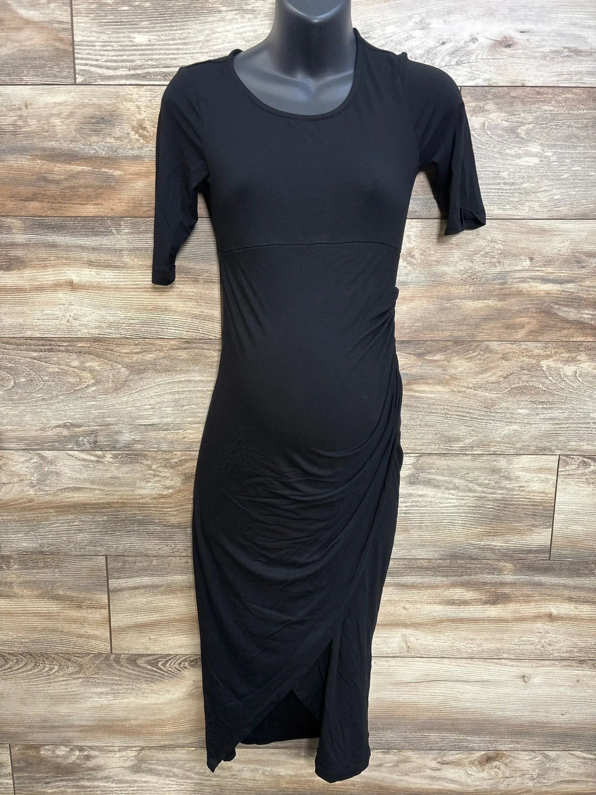 Front view of Isabella Oliver black maternity short-sleeve midi dress showing side ruching and tulip wrap hem on mannequin
