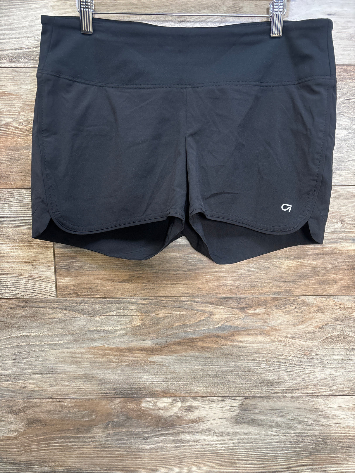 Front view of GapFit maternity running shorts showing wide foldover waistband, curved hem and built-in liner on wood background