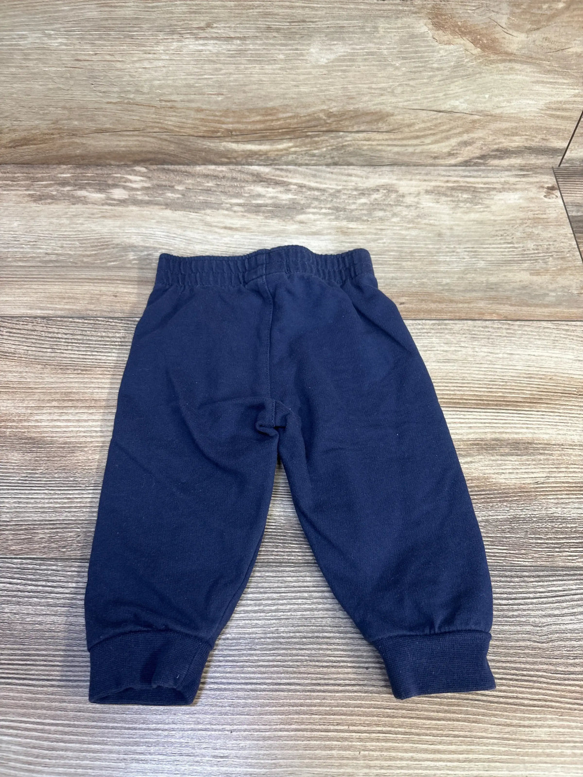 Front view of Nike navy baby pull-on joggers size 6 months showcasing elastic waistband and cuffed ankles on white background