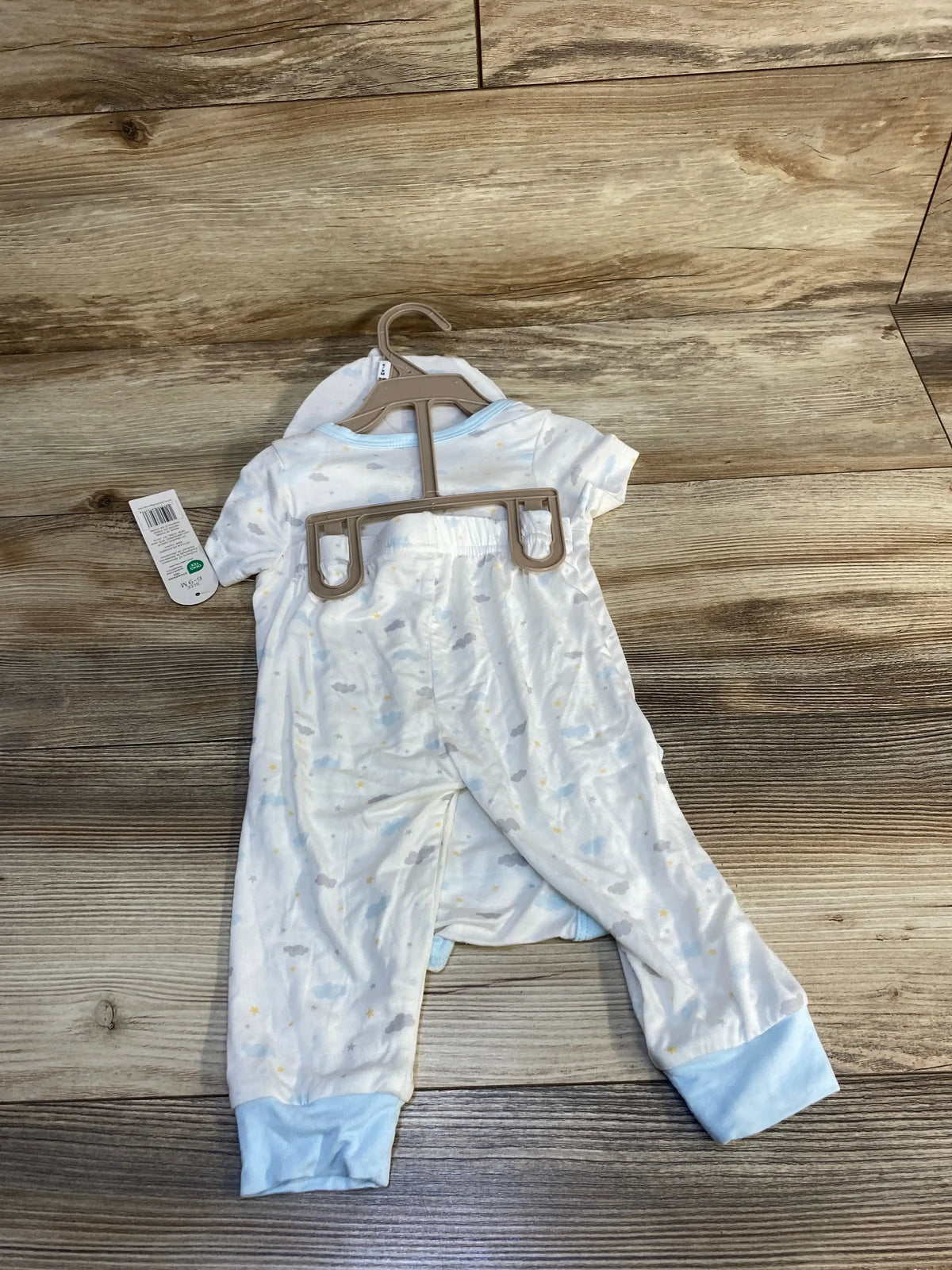 Blue and white baby sleeper with cloud print and footed cuffs displayed on wood floor