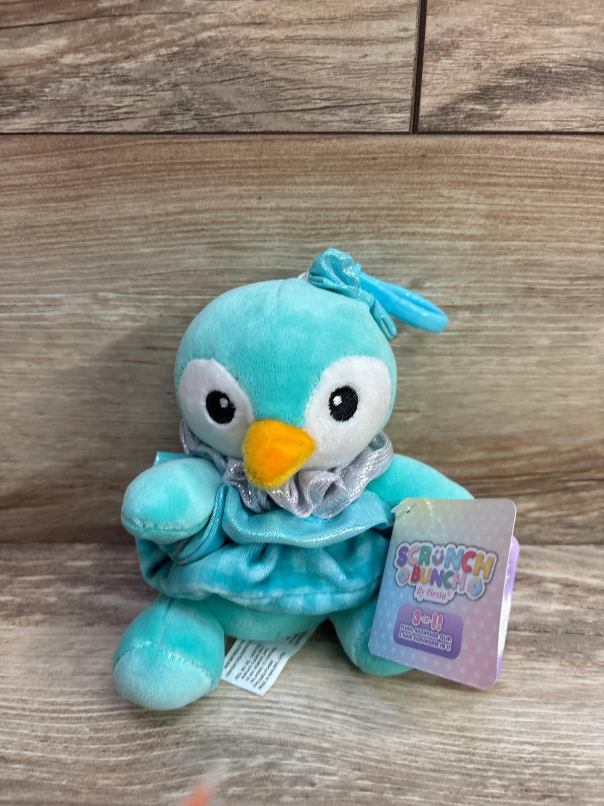 Aqua blue plush penguin toy with yellow beak, bow, ruffled collar, and Scrunch Bunch tag