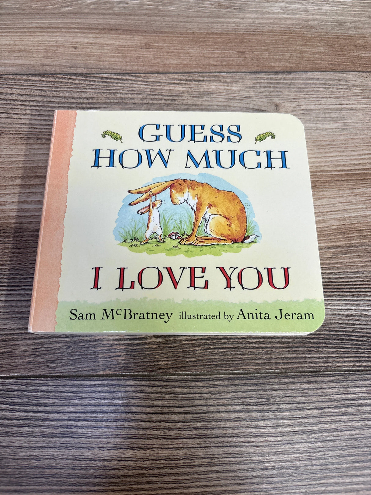 Guess How Much I Love You children's book cover on wood background, featuring two rabbits.