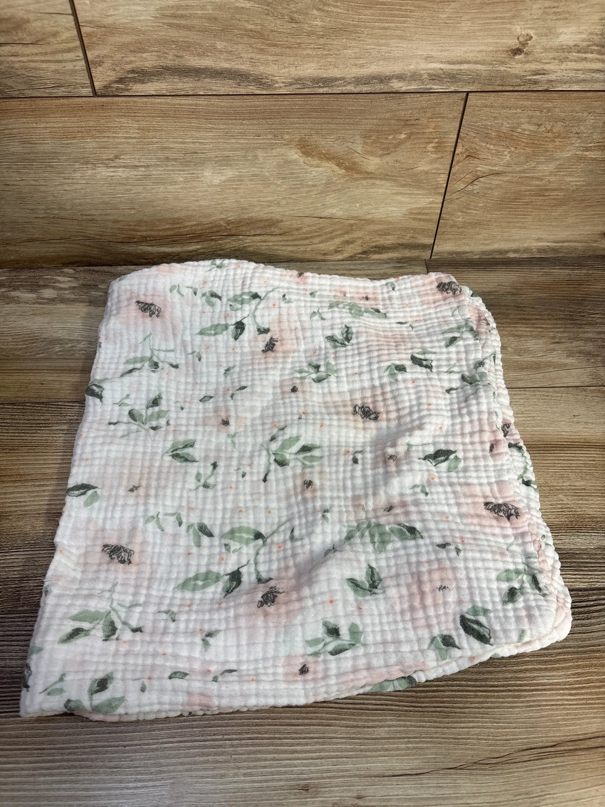 Top view of Pottery Barn Kids Organic Changing Pad Cover White showcasing floral pattern and elastic edges on wood floor