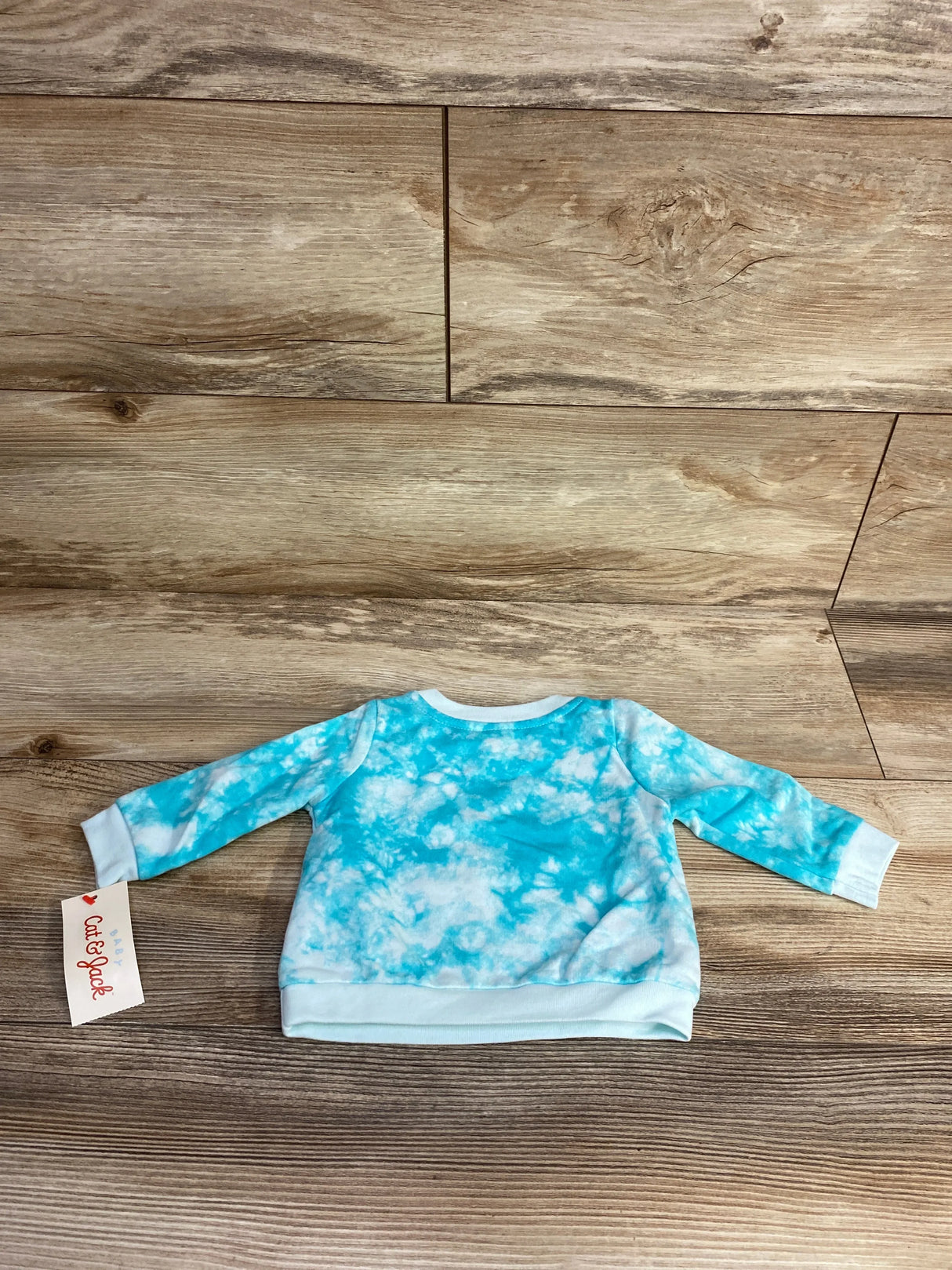 Blue and white tie-dye baby sweatshirt with long sleeves on wood background