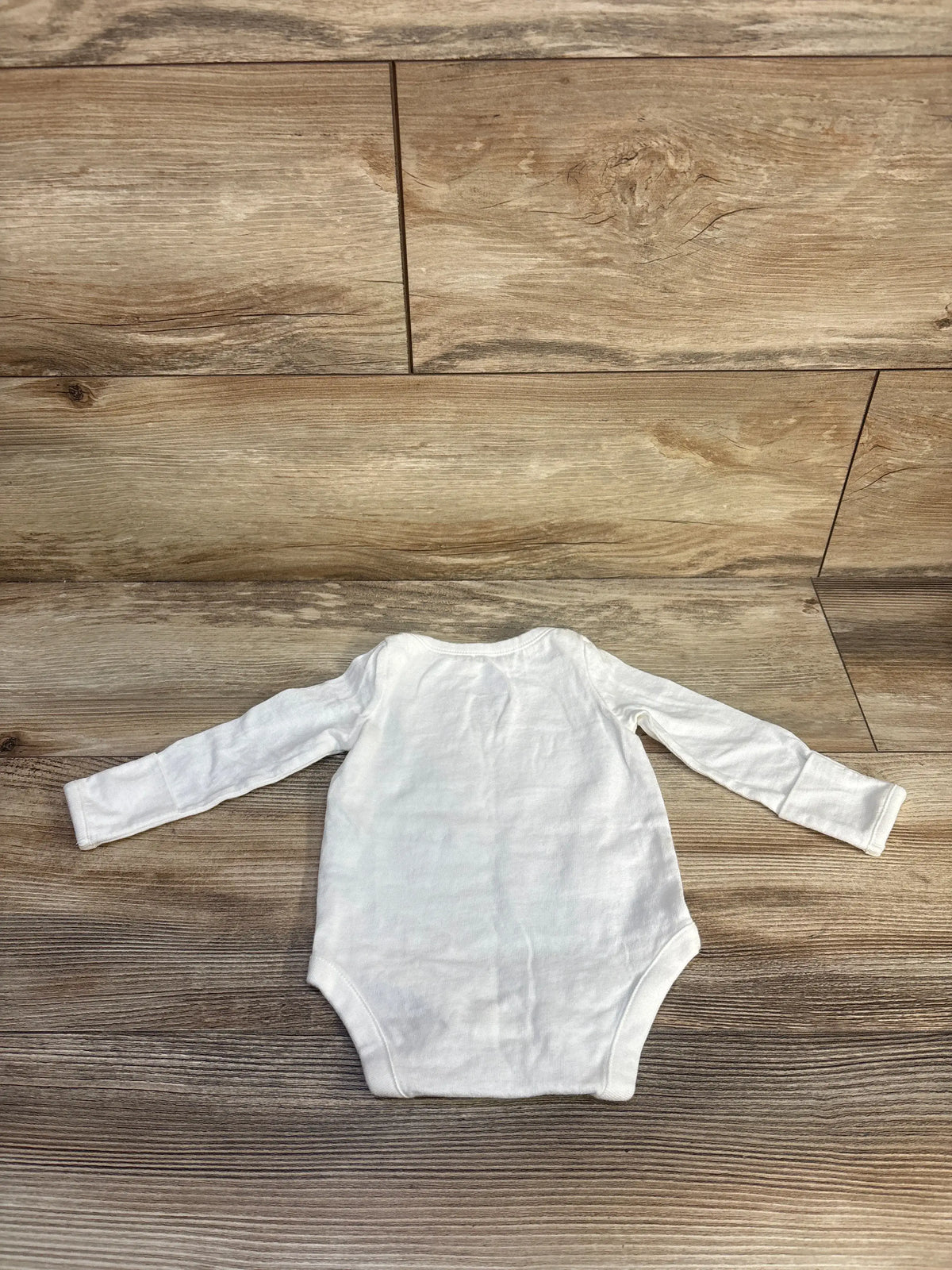 Front view of Baby Gap white long sleeve bodysuit for 0-3 months showcasing long sleeves on a wood floor